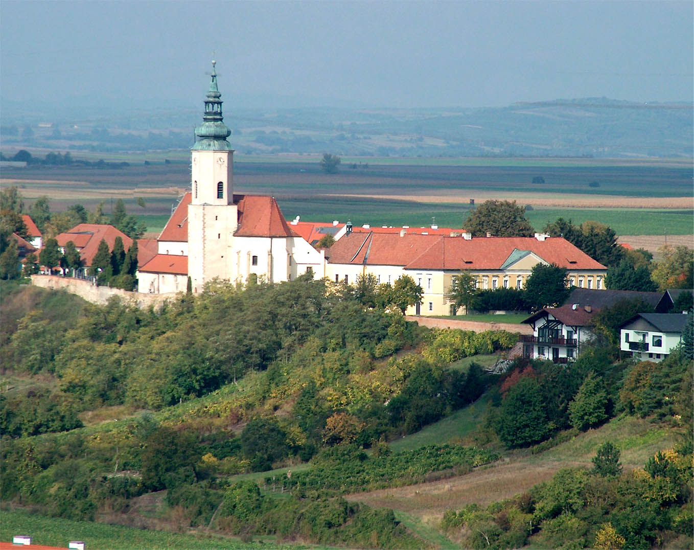 Farský kostol svätej Agáty na kopci s okolitými budovami a krajinou v pozadí.