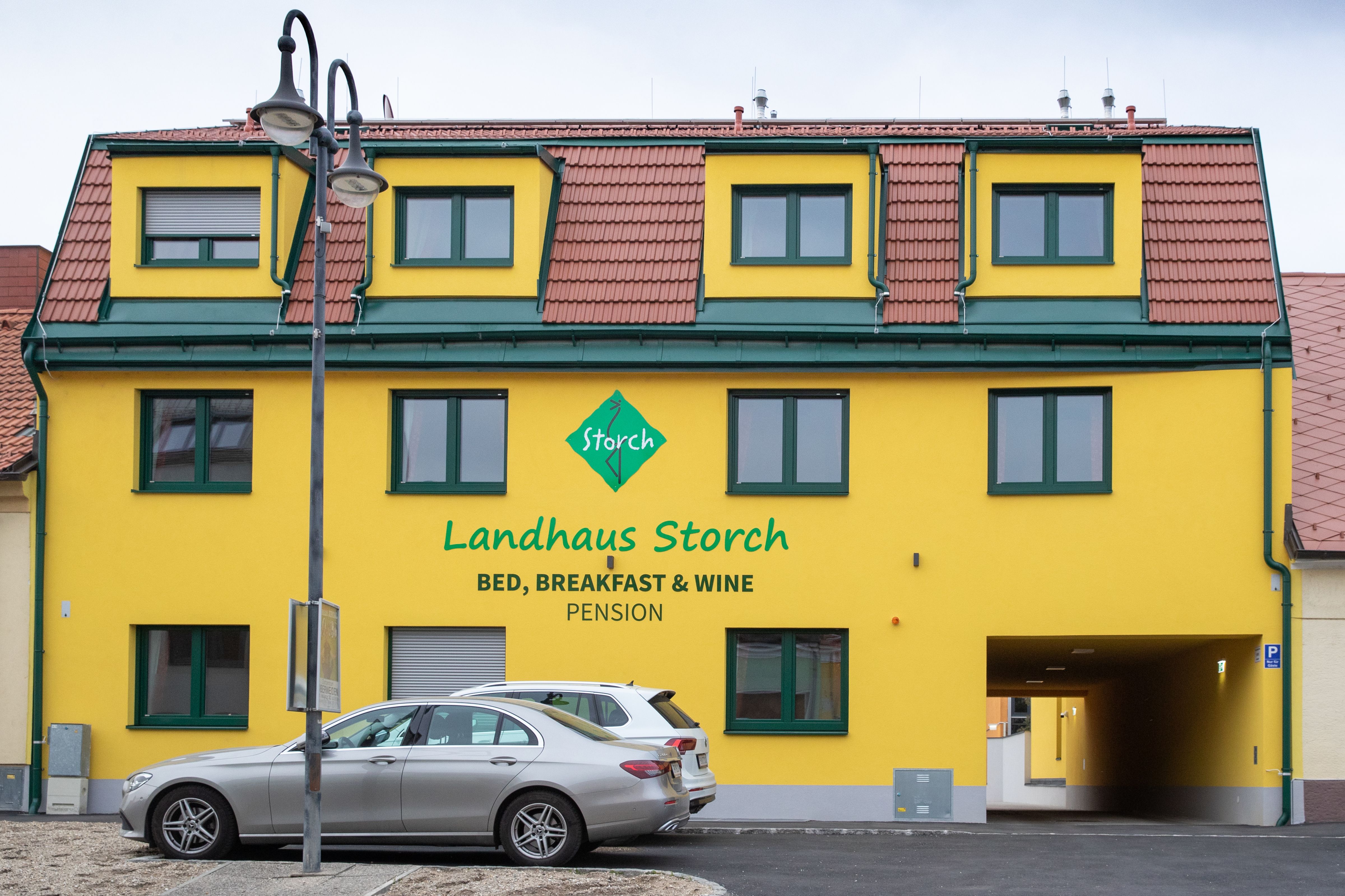 Žltá budova s nápisom "Landhaus Storch", pred ňou zaparkované autá.