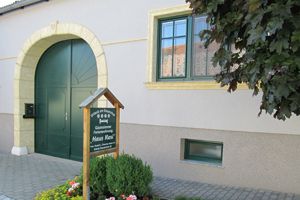 Vchod do penziónu so zelenou bránou a nápisom "Haus Resi".