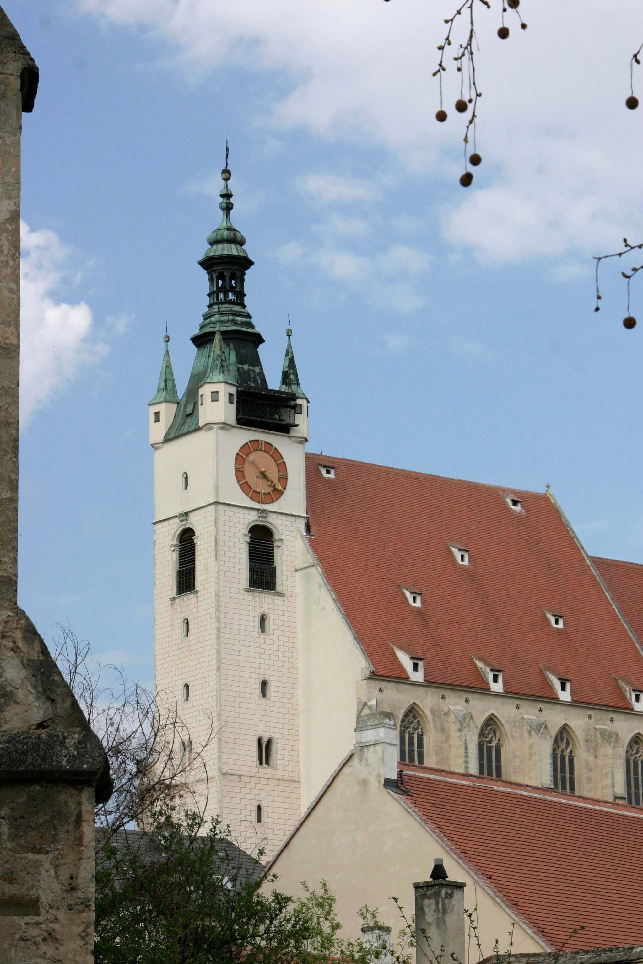 Piaristický kostol s vežou a hodinami na pozadí modrej oblohy.