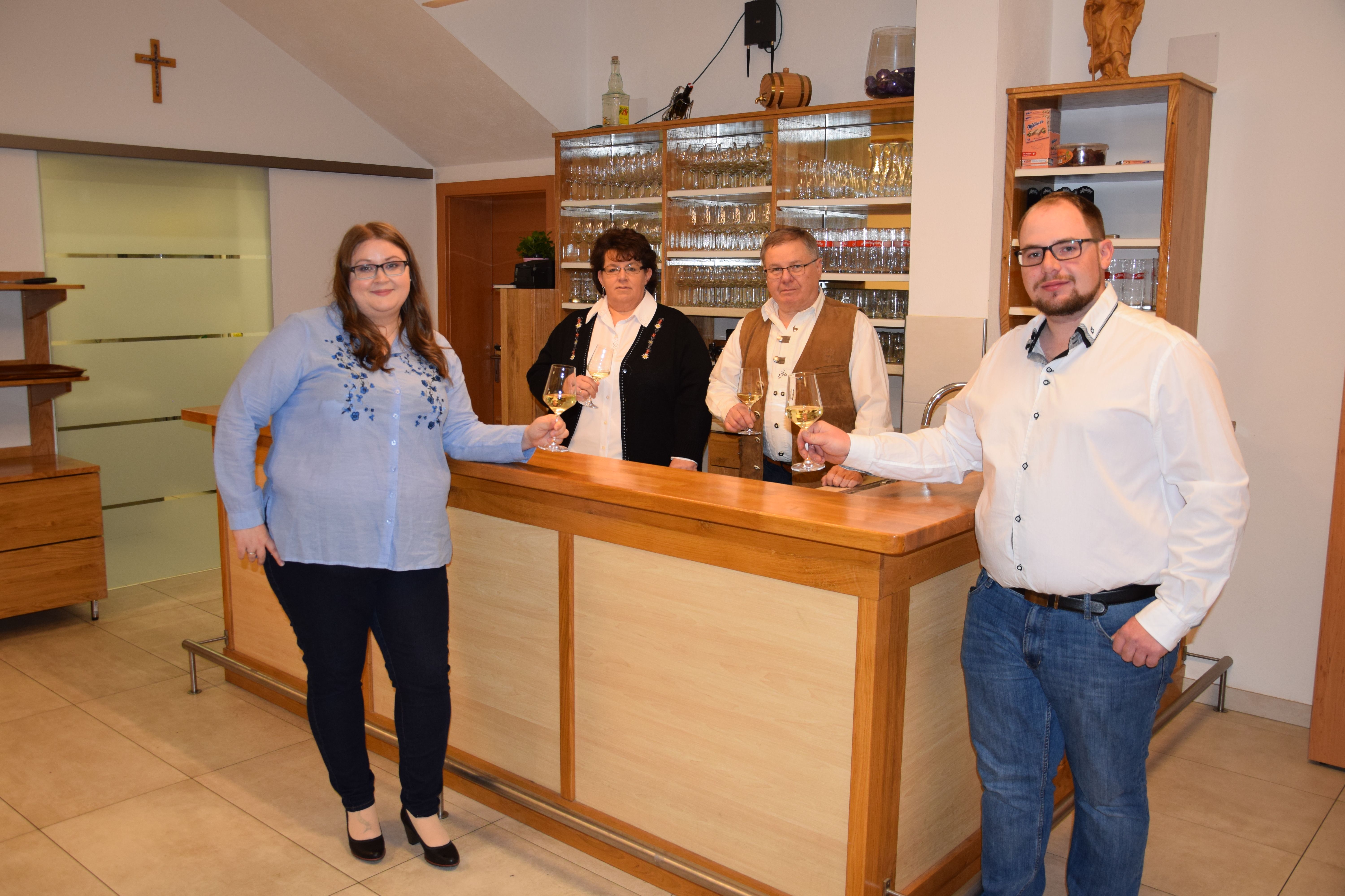 Štyria ľudia stoja pri bare a držia poháre s vínom.