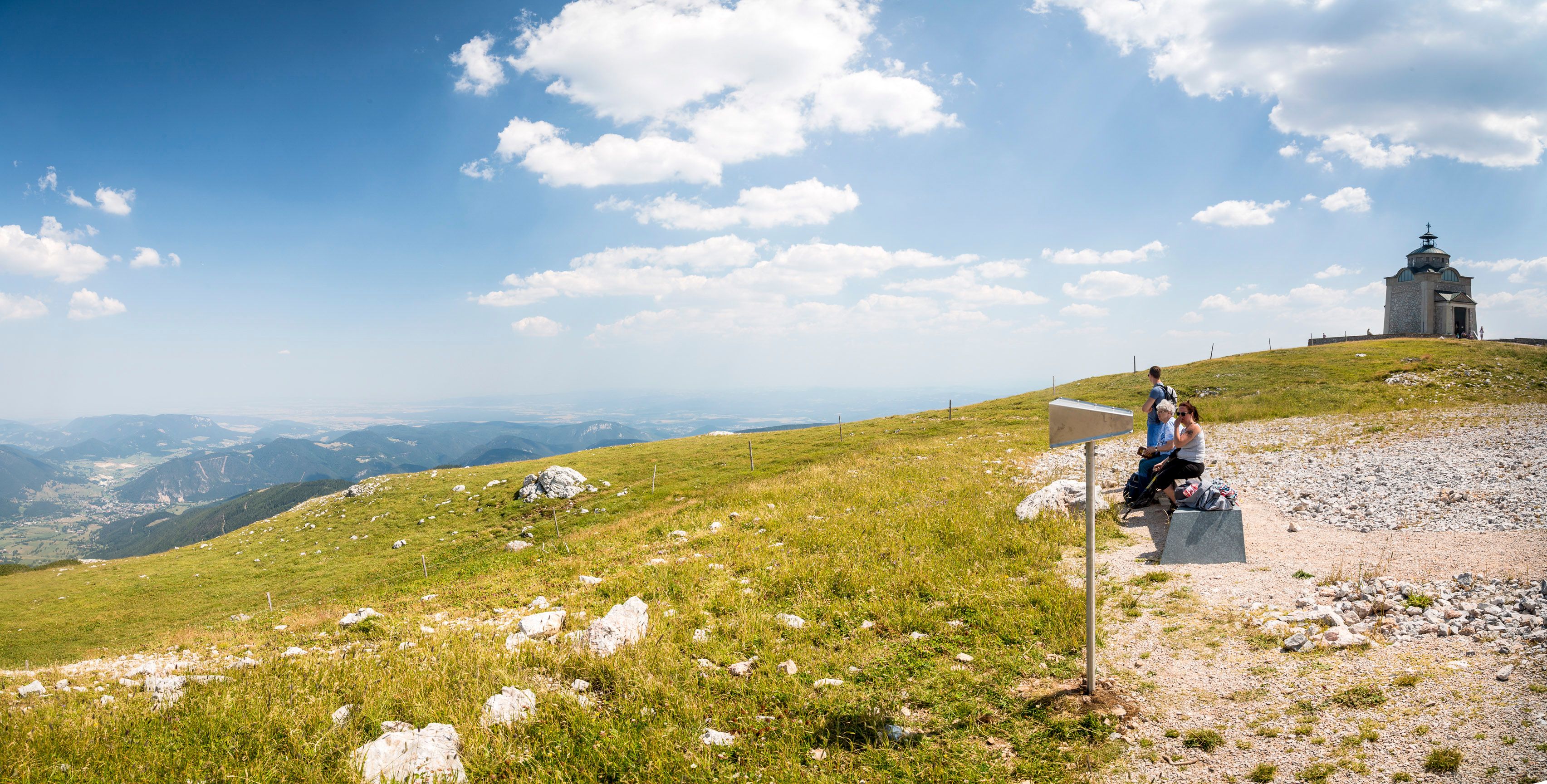 Panoramatický pohľad na Alžbetin kostol na Schneebergu s turistami v popredí.