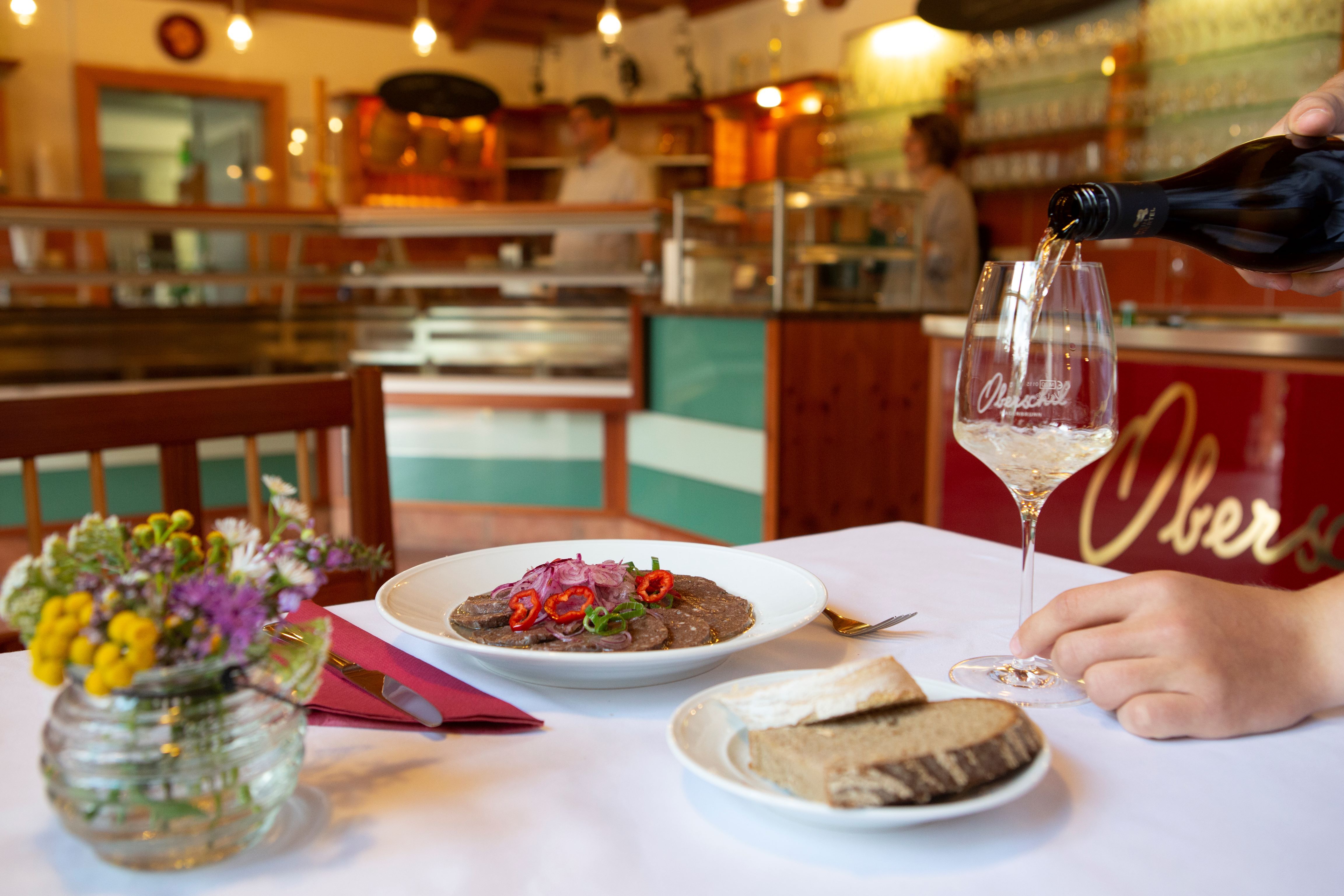 Položený stôl vo vinárni s tanierom jedla, chlebom a pohárom vína.