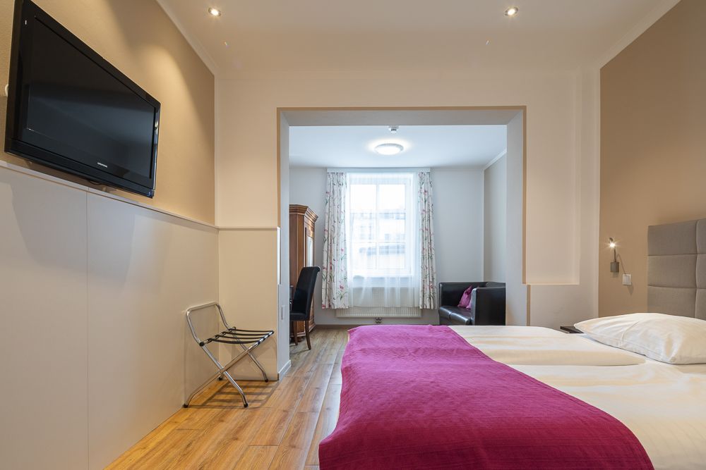 Hotelová izba s manželskou posteľou, TV a priestorom na posedenie.