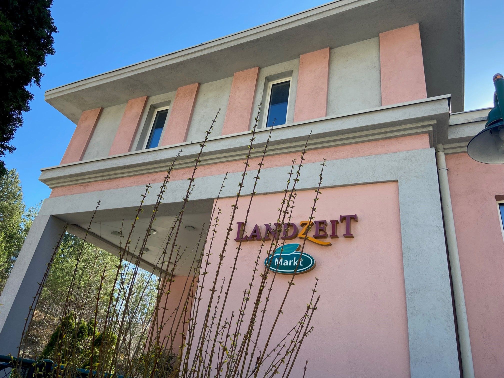 Budova s ružovou a sivou fasádou, nápis "Landzeit Markt".