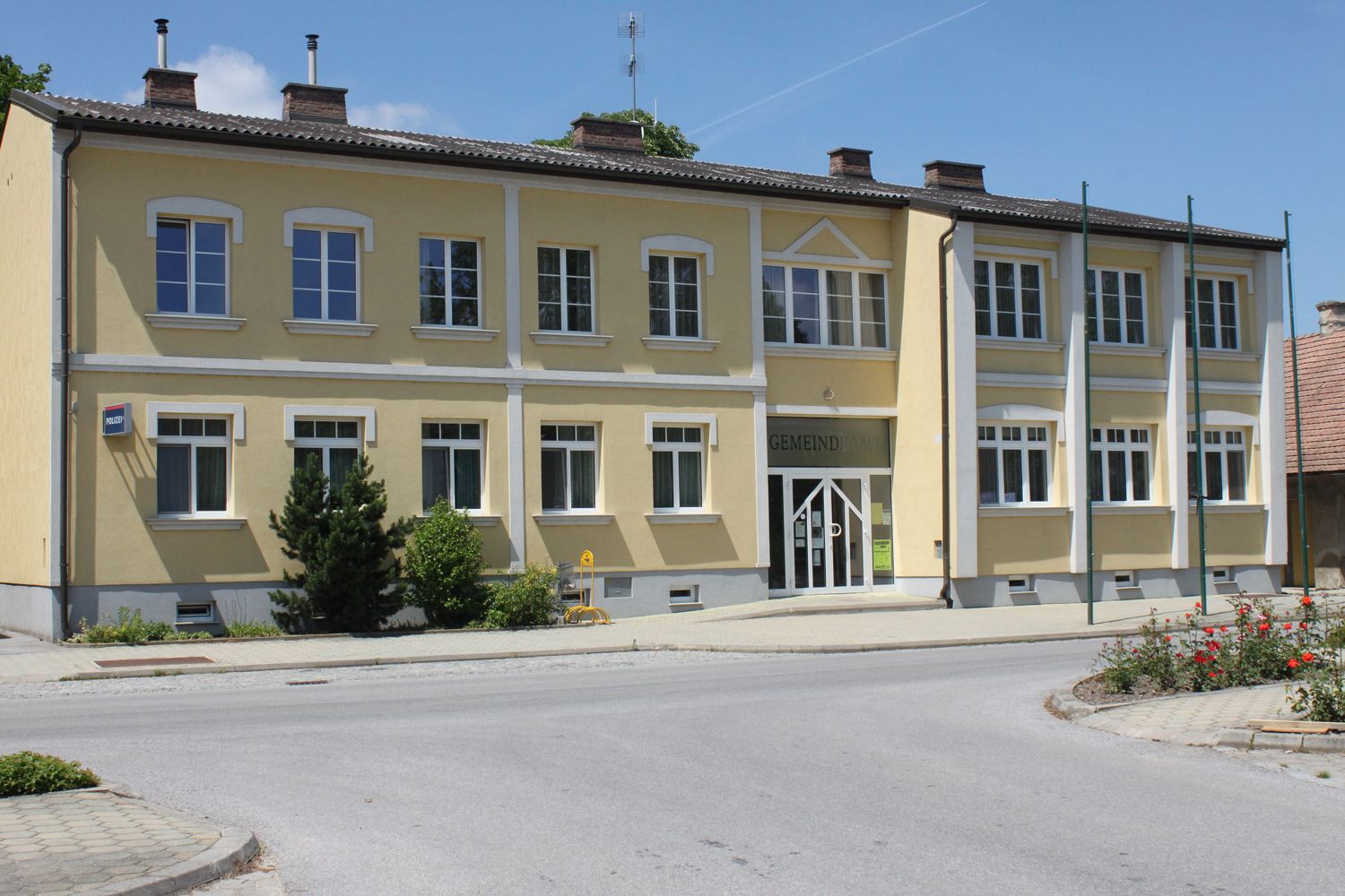 Žltá budova s nápisom "Gemeindeamt" a niekoľkými oknami.