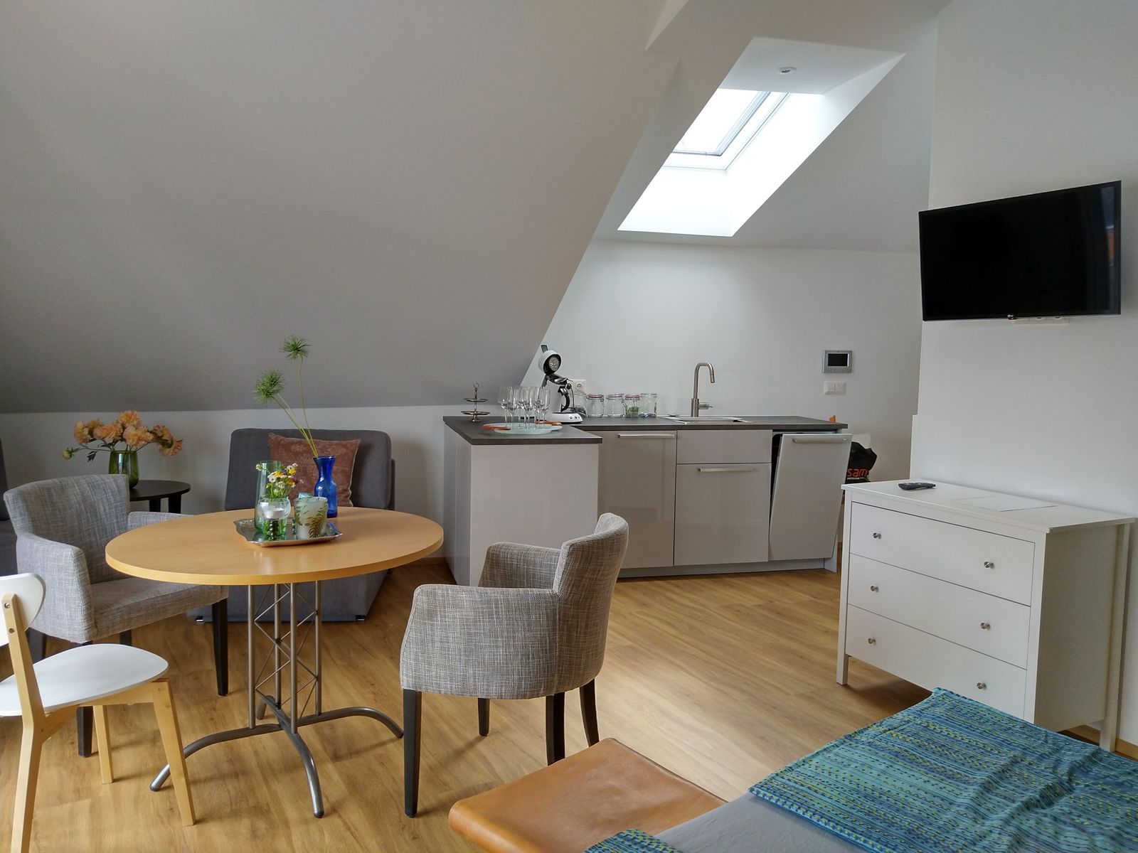 Moderný byt s kuchynským kútom, jedálenským stolom a TV.