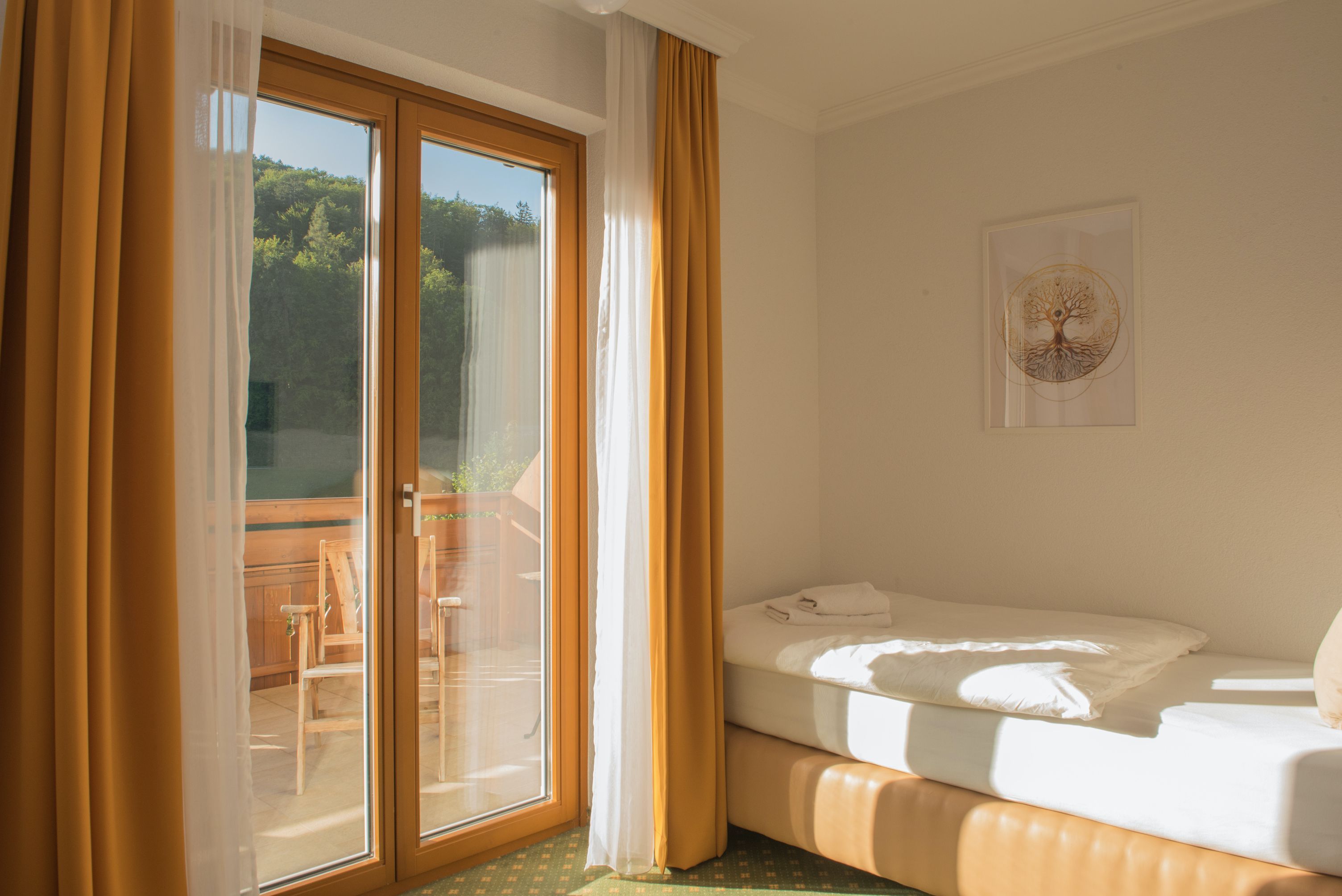 Jednolôžková izba s balkónom, posteľ, žlté závesy, drevený balkón, slnečná.