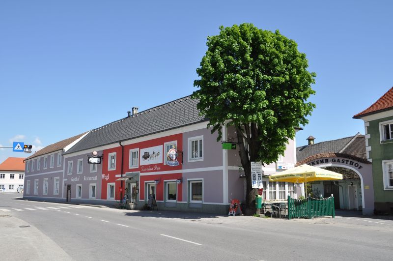 Gasthof Wegl na ceste so stromom a slnečníkmi.