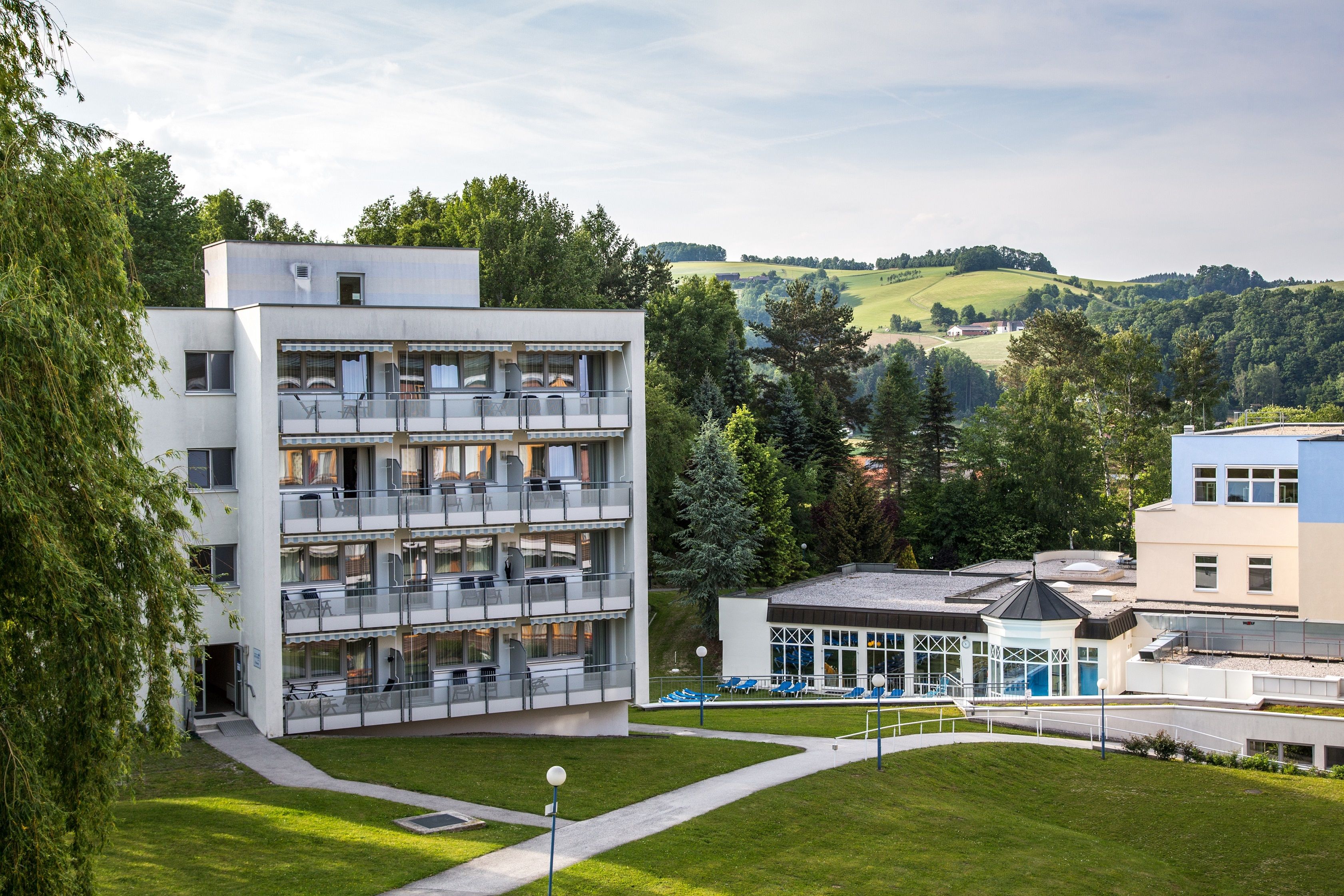 Exteriérový pohľad na Parkhotel v kúpeľoch Königsberg s okolitou zelenou krajinou.
