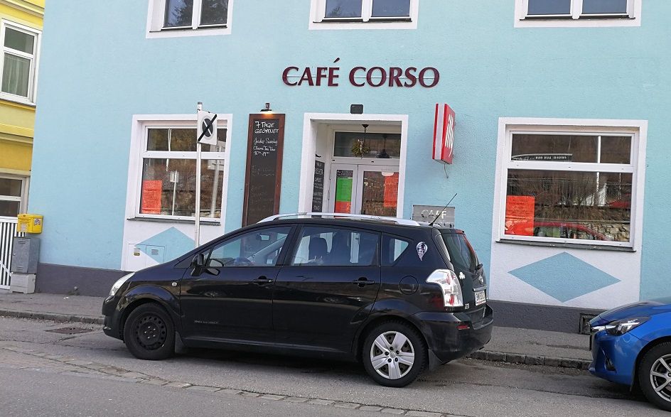 Exteriérový pohľad na kaviareň Café Corso so zaparkovaným autom vpredu.