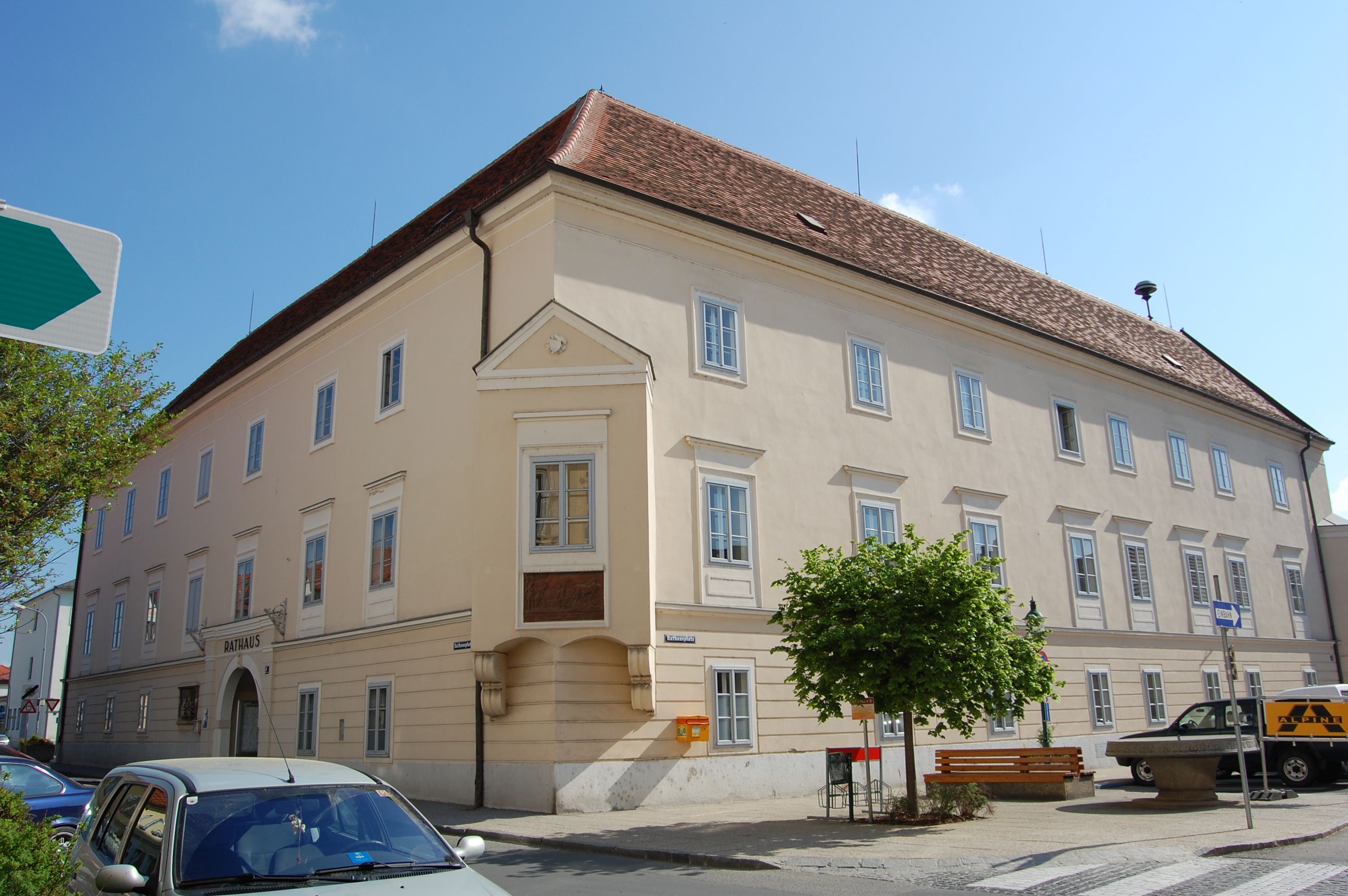 Veľká svetlá budova s červenými škridlami a mnohými oknami, označená ako "radnica".