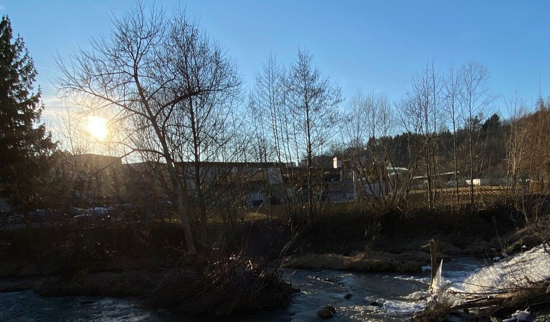 Západ slnka za stromami a riekou v údolí Zwettltal.