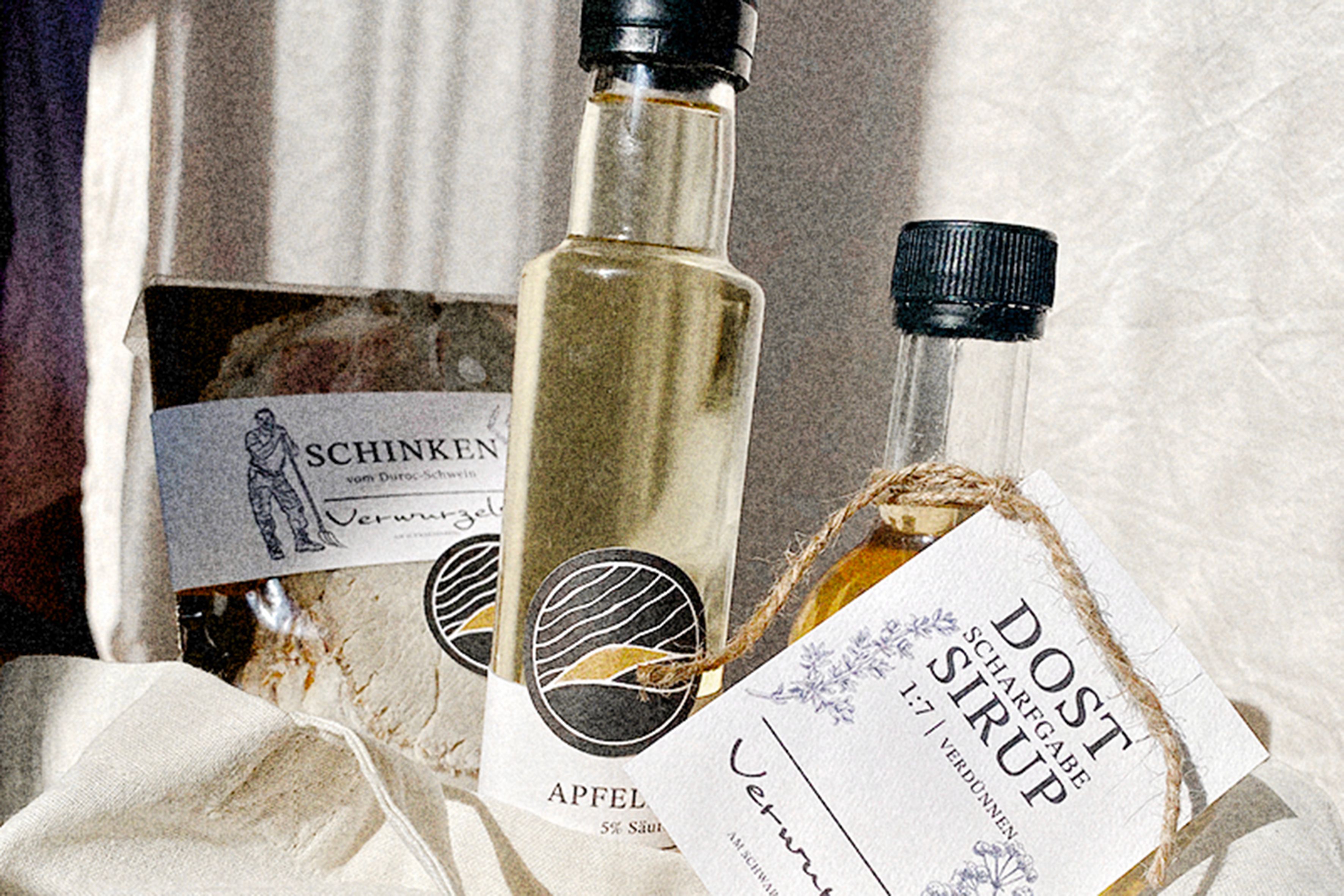 Detailný záber na šunku, jablčný ocot a sirup s etiketami na utierke.