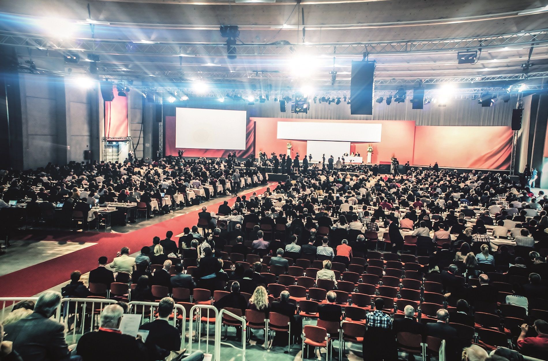 Veľká kongresová sála s mnohými účastníkmi, pódiom a obrazovkou.