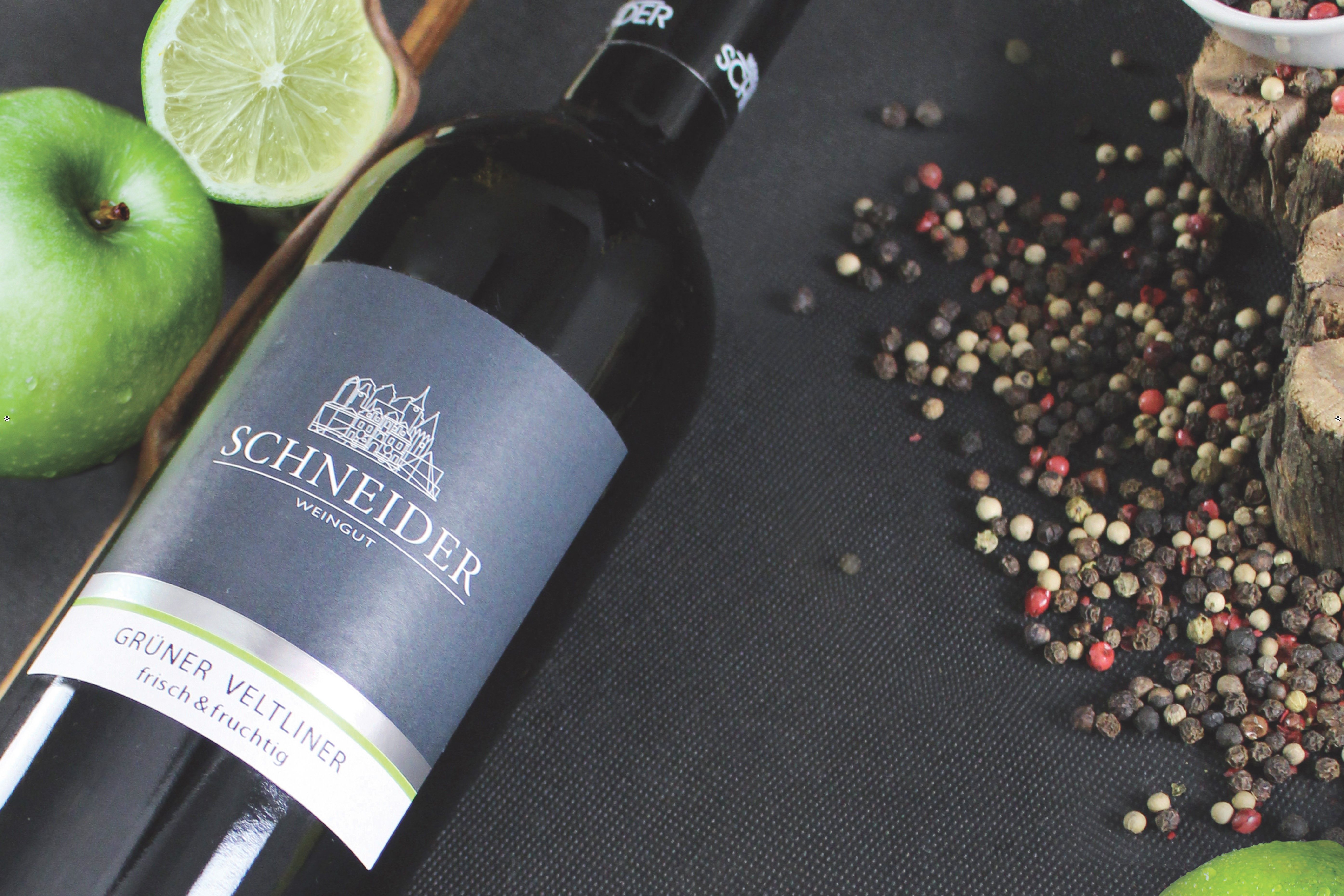 Fľaša vína veltlínske zelené od Weingut Schneider so zeleným jablkom a limetkou.