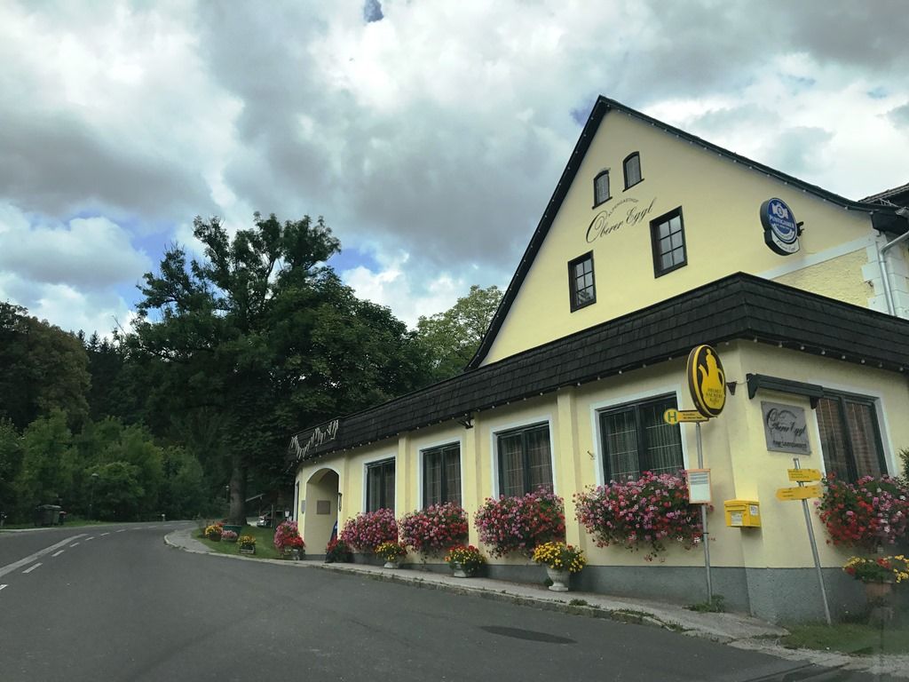 Gasthof Oberer Eggl s kvetmi a autobusovou zastávkou.
