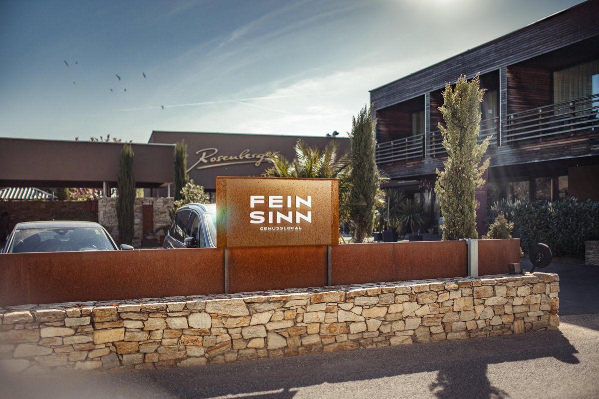 Vstup do Feinsinn Genusslokal s modernou architektúrou a rastlinami.