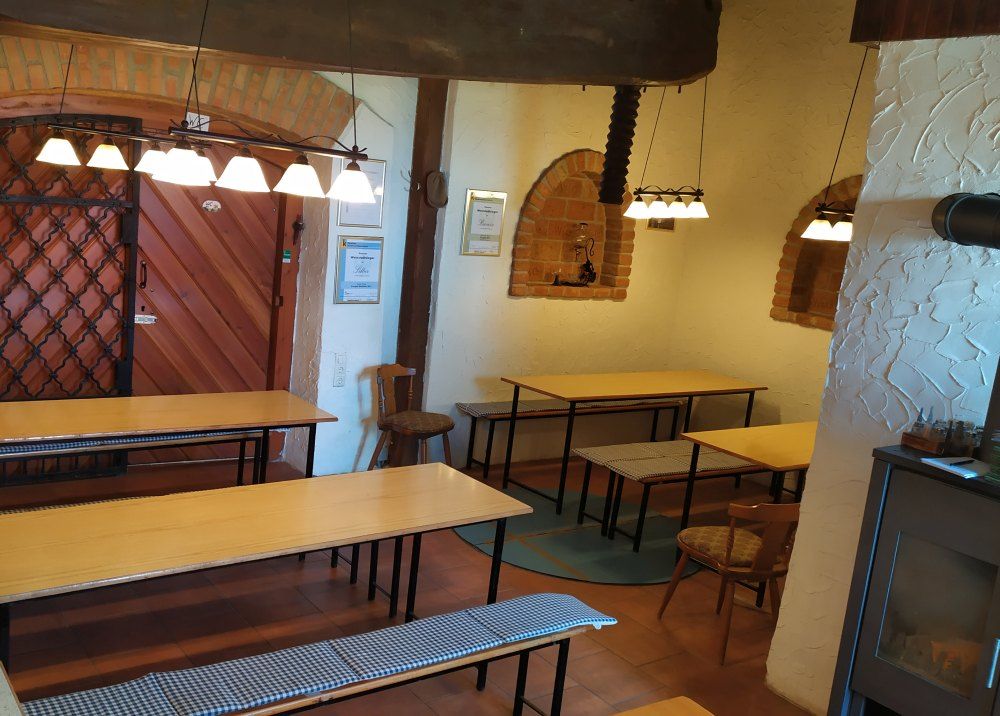 Pohľad do interiéru Viechy s drevenými stolmi, lavicami a rustikálnou výzdobou.