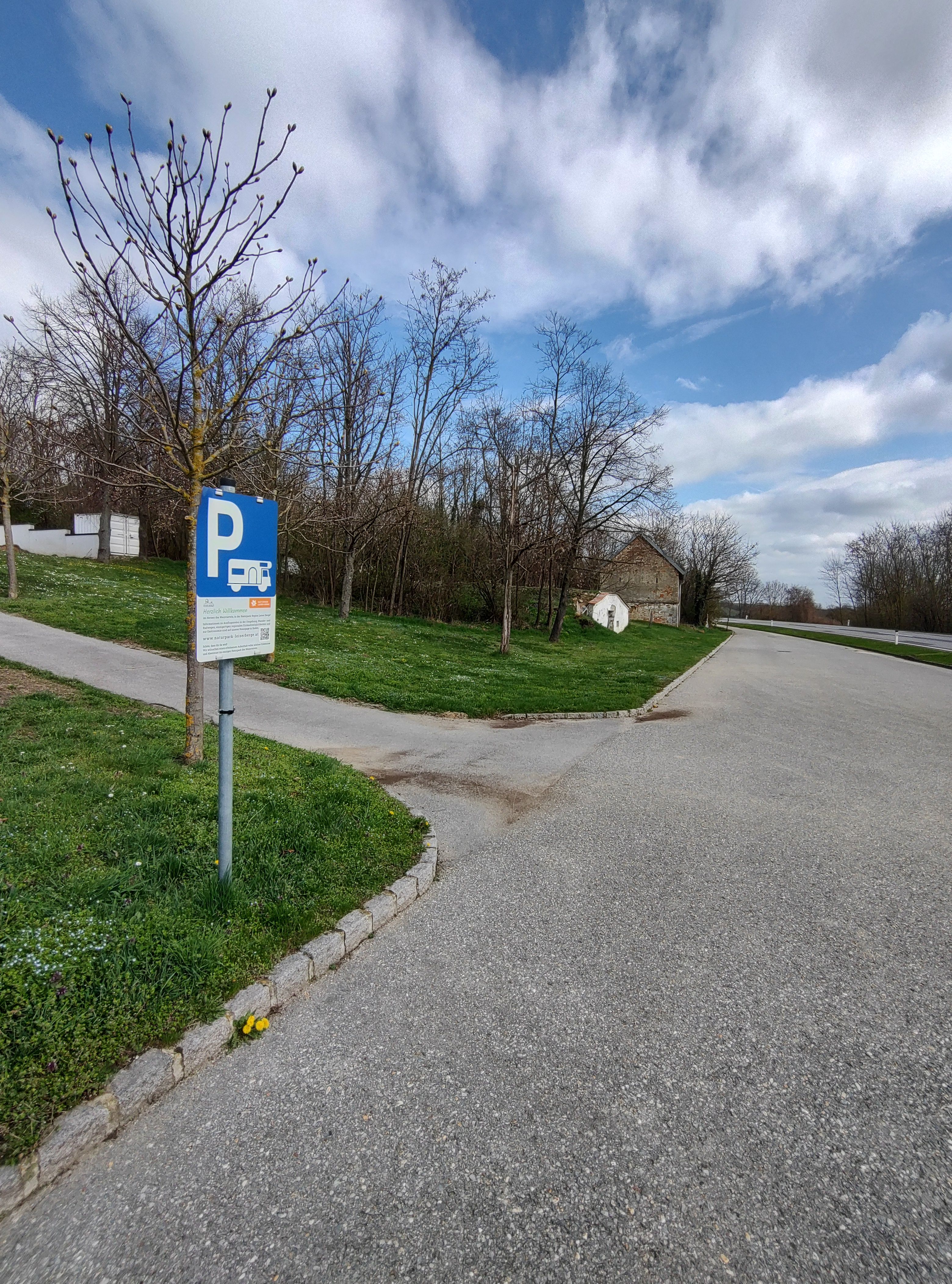 Kemp pre karavany so značkou parkoviska a stromami v pozadí.