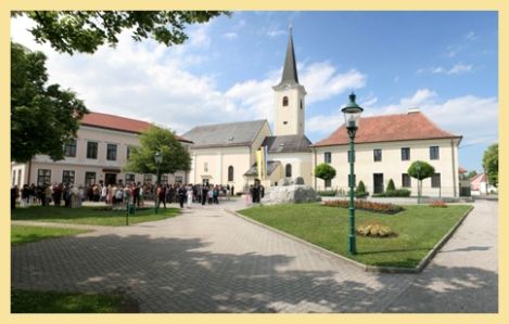 Farský kostol v Absdorfe s okolitým námestím a zhromaždením ľudí.
