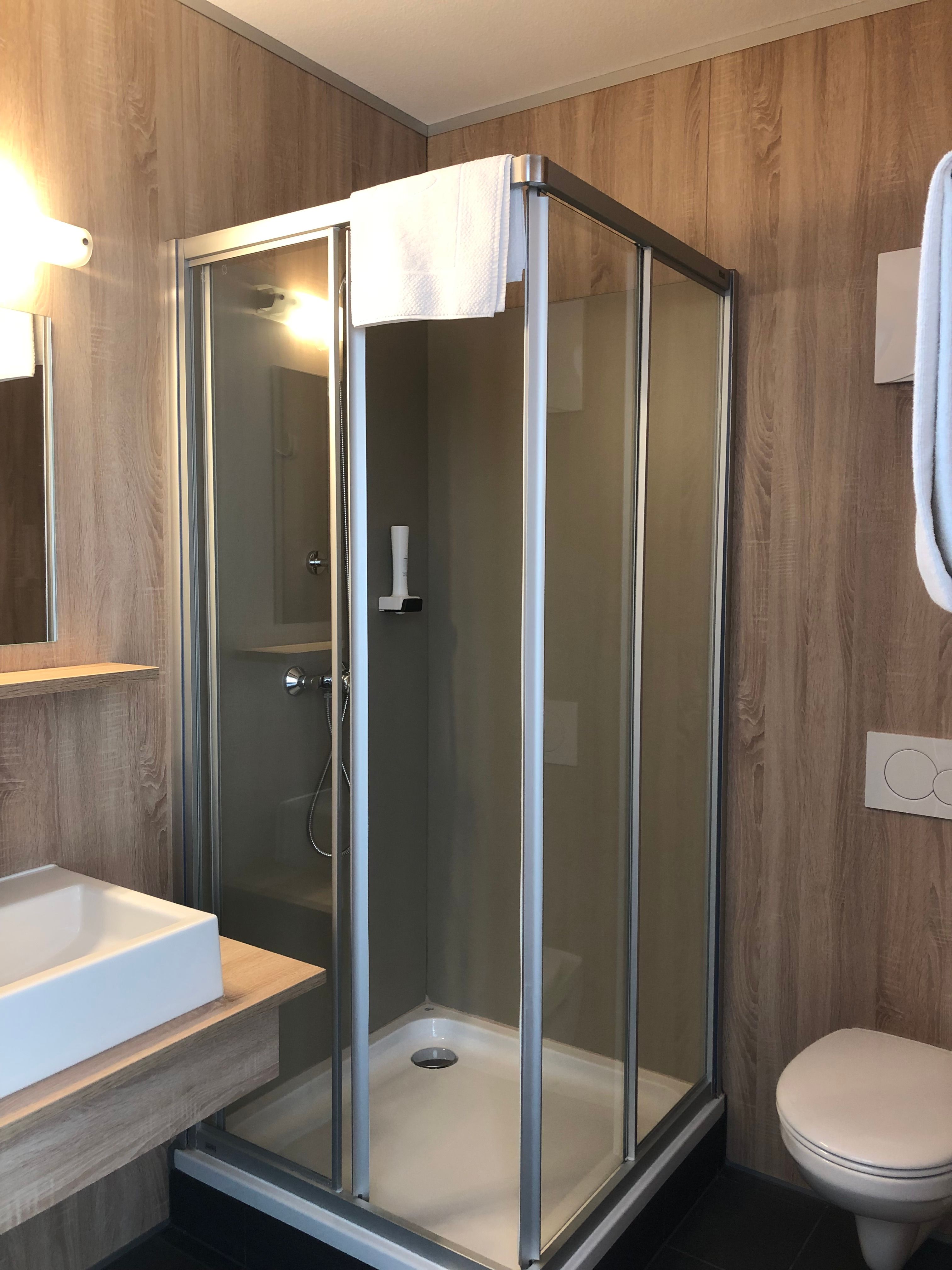 Moderná kúpeľňa so sprchovacím kútom, umývadlom a WC.