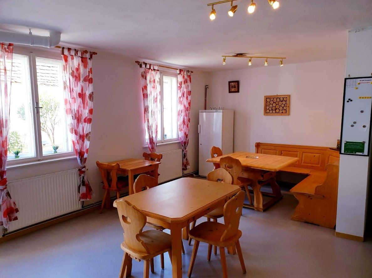 Útulná izba s dreveným nábytkom a červenými závesmi.