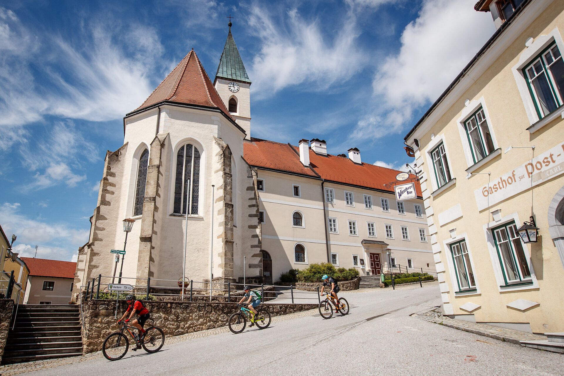Zvlnené kopce vás pozývajú na nezabudnuteľné dobrodružstvo a malebná architektúra okolia vytvára harmonickú kulisu. Cyklisti sa kĺžu po ceste, aby si vychutnali úchvatný výhľad na okolitú prírodu. Tu, kde sa stretávajú tradície a príroda, je každý okamih zážitkom.