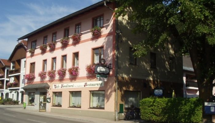 Tradičný hostinec s ružovou fasádou a kvetinovými truhlicami na oknách.
