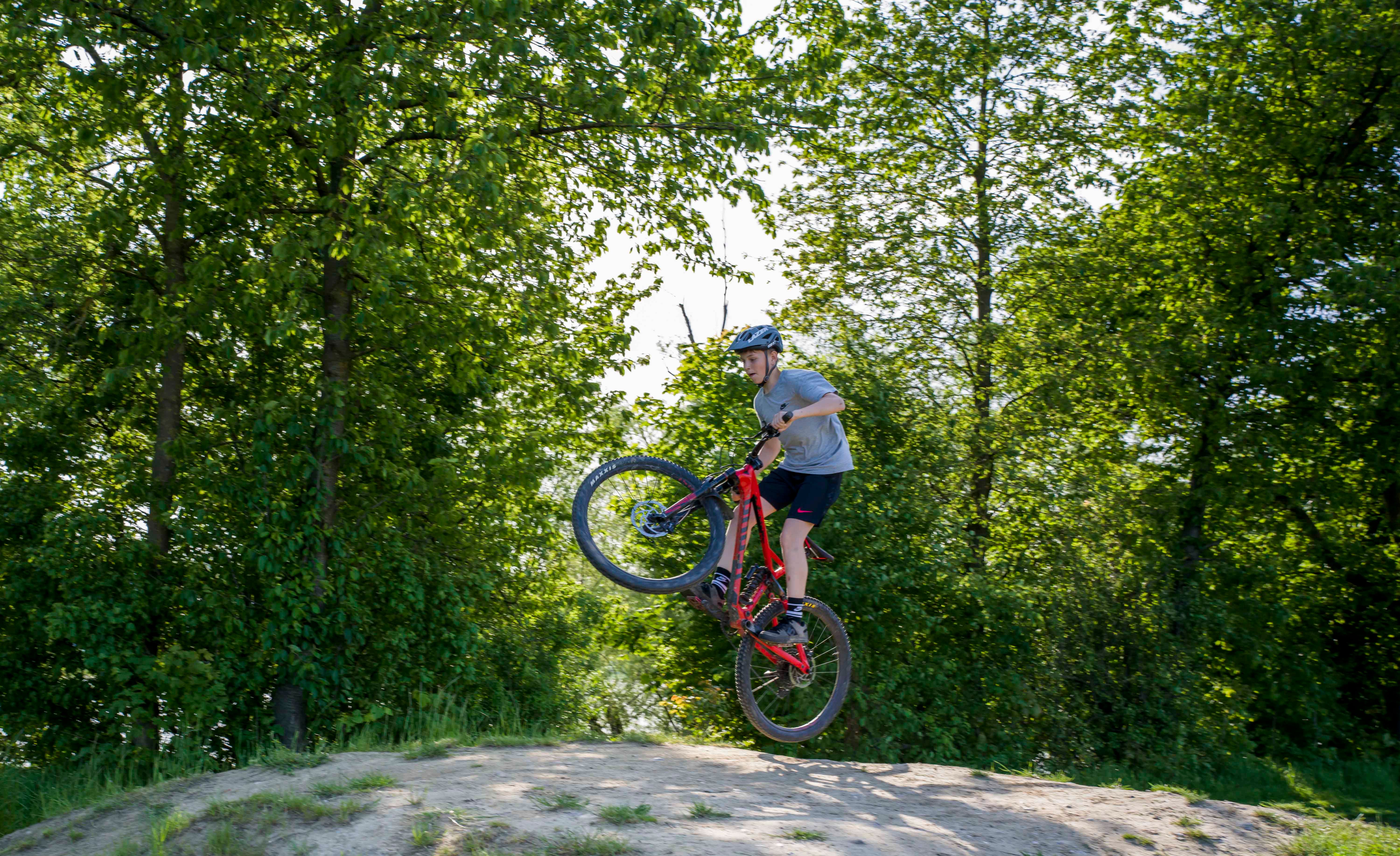Osoba na horskom bicykli skáče v zalesnenej oblasti.