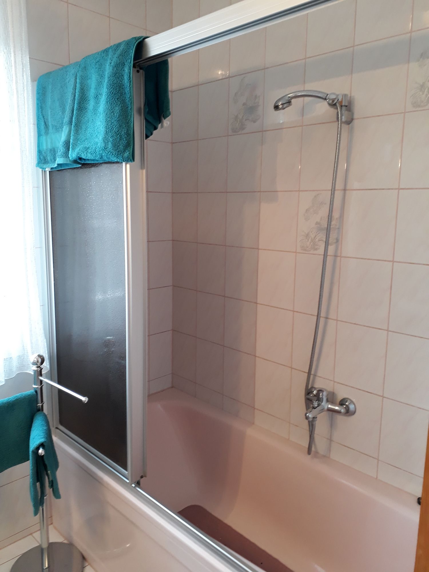 Kúpeľňa s vaňou, sprchovým závesom a modrými uterákmi.