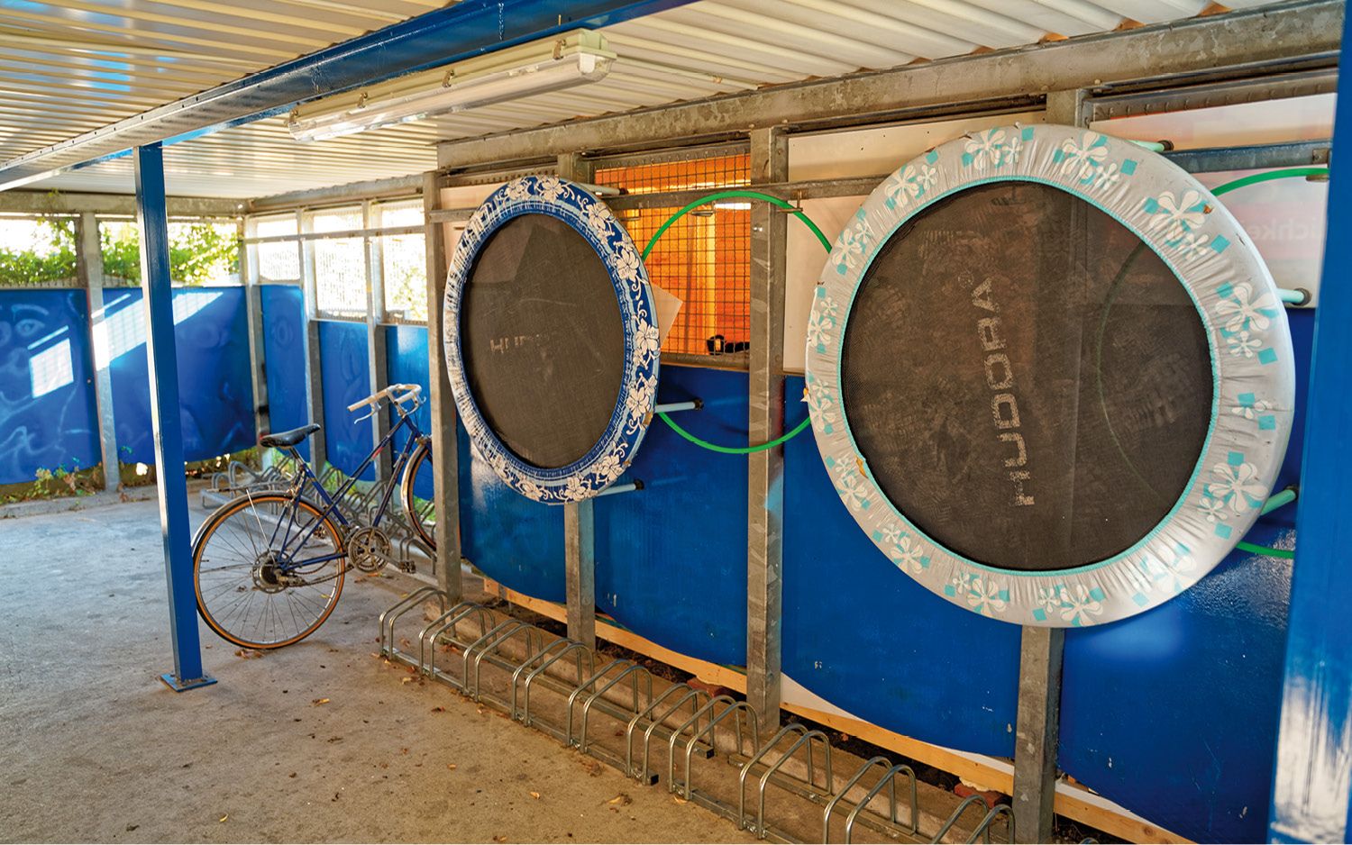 Garáž pre bicykle s trampolínami na stene.