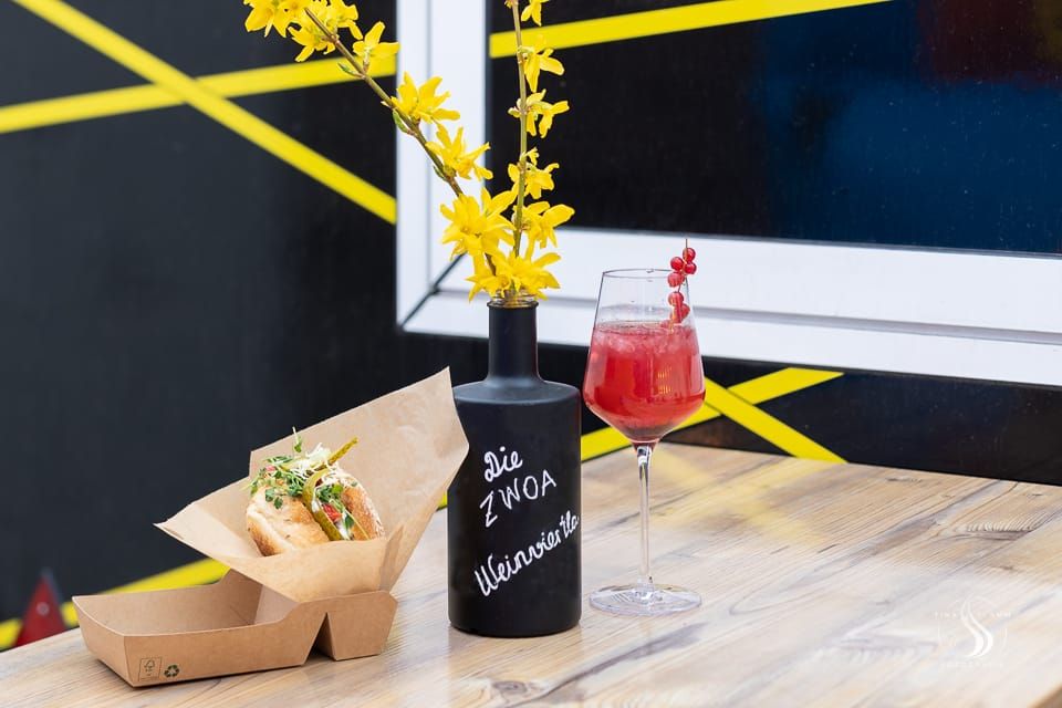 Nápoj a sendvič na stole s vázou so žltými kvetmi.