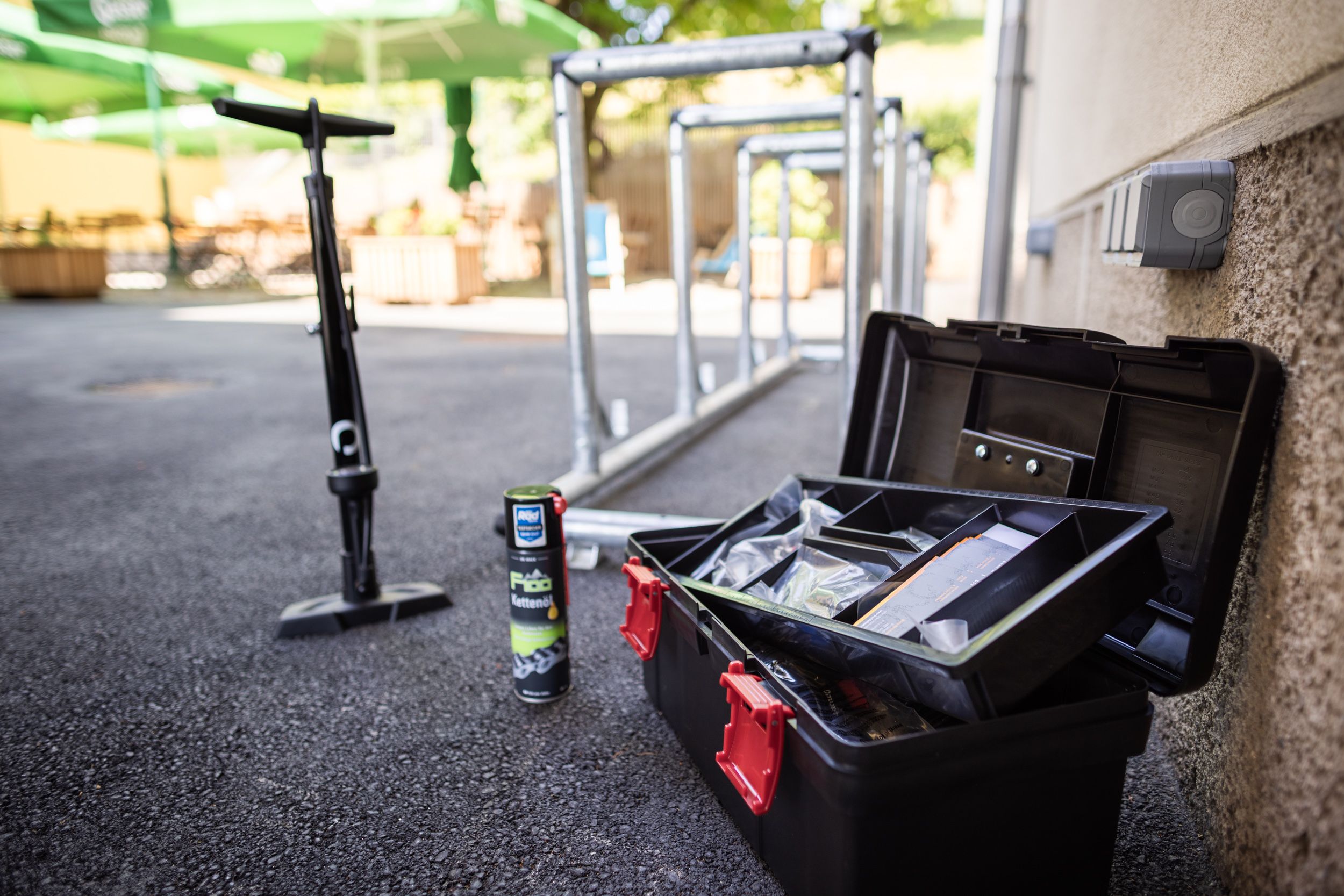 Náradie na bicykle, olej na reťaze a pumpa vedľa stojanov na bicykle vonku.