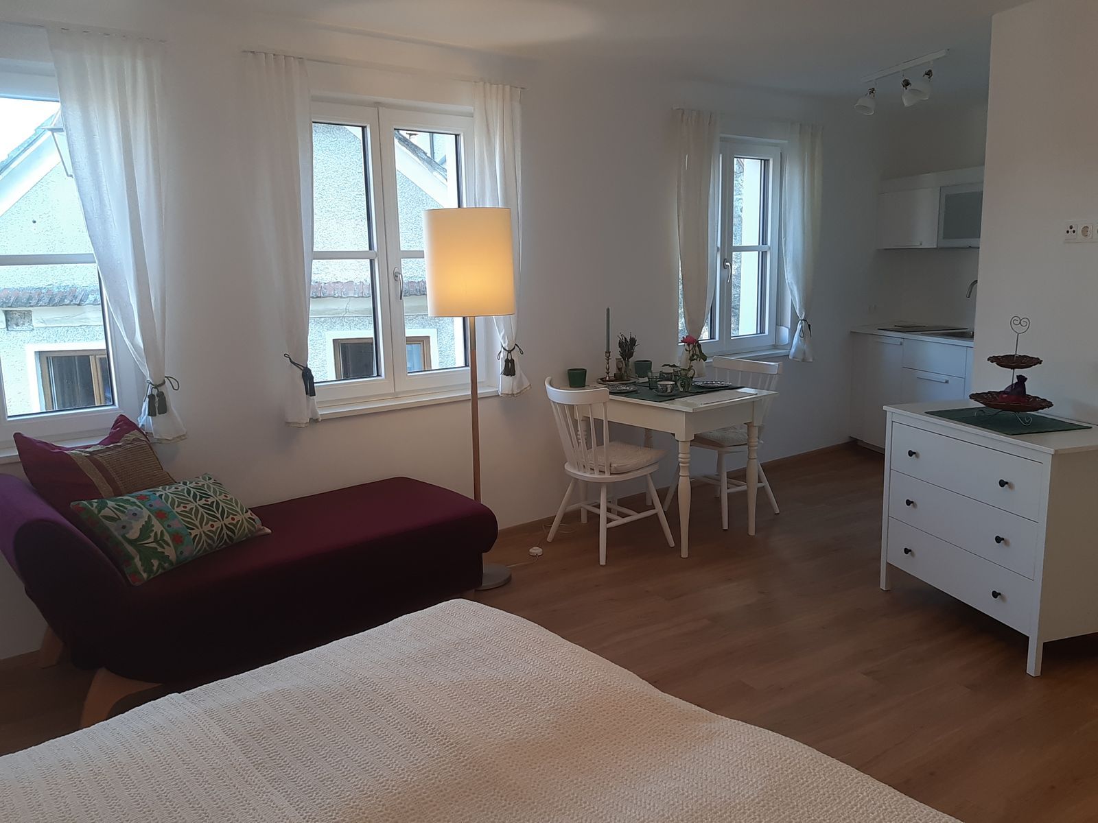 Svetlý byt s pohovkou, jedálenským stolom a kuchynským kútom.