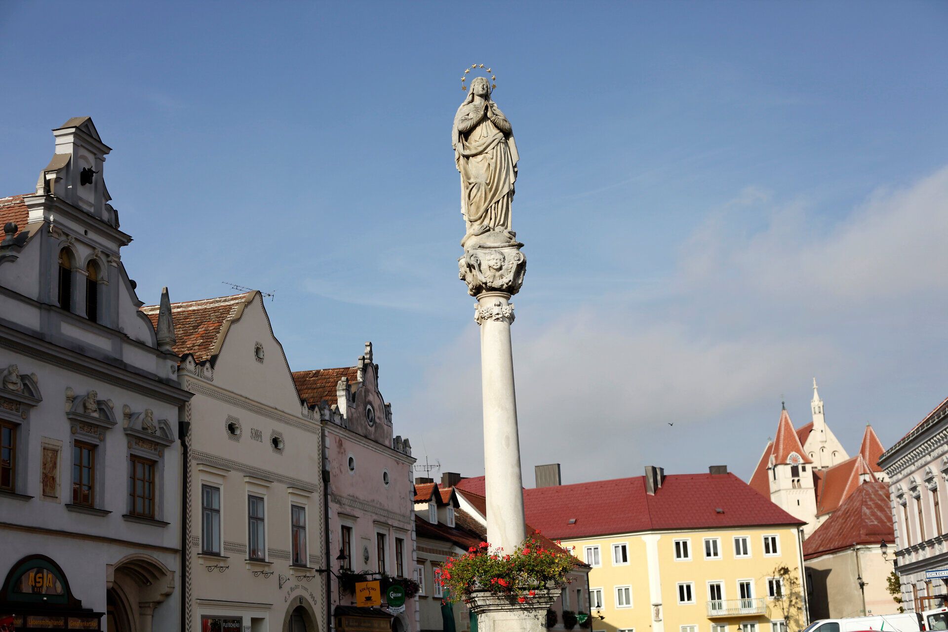 Socha na stĺpe v Eggenburgu s historickými budovami v pozadí.