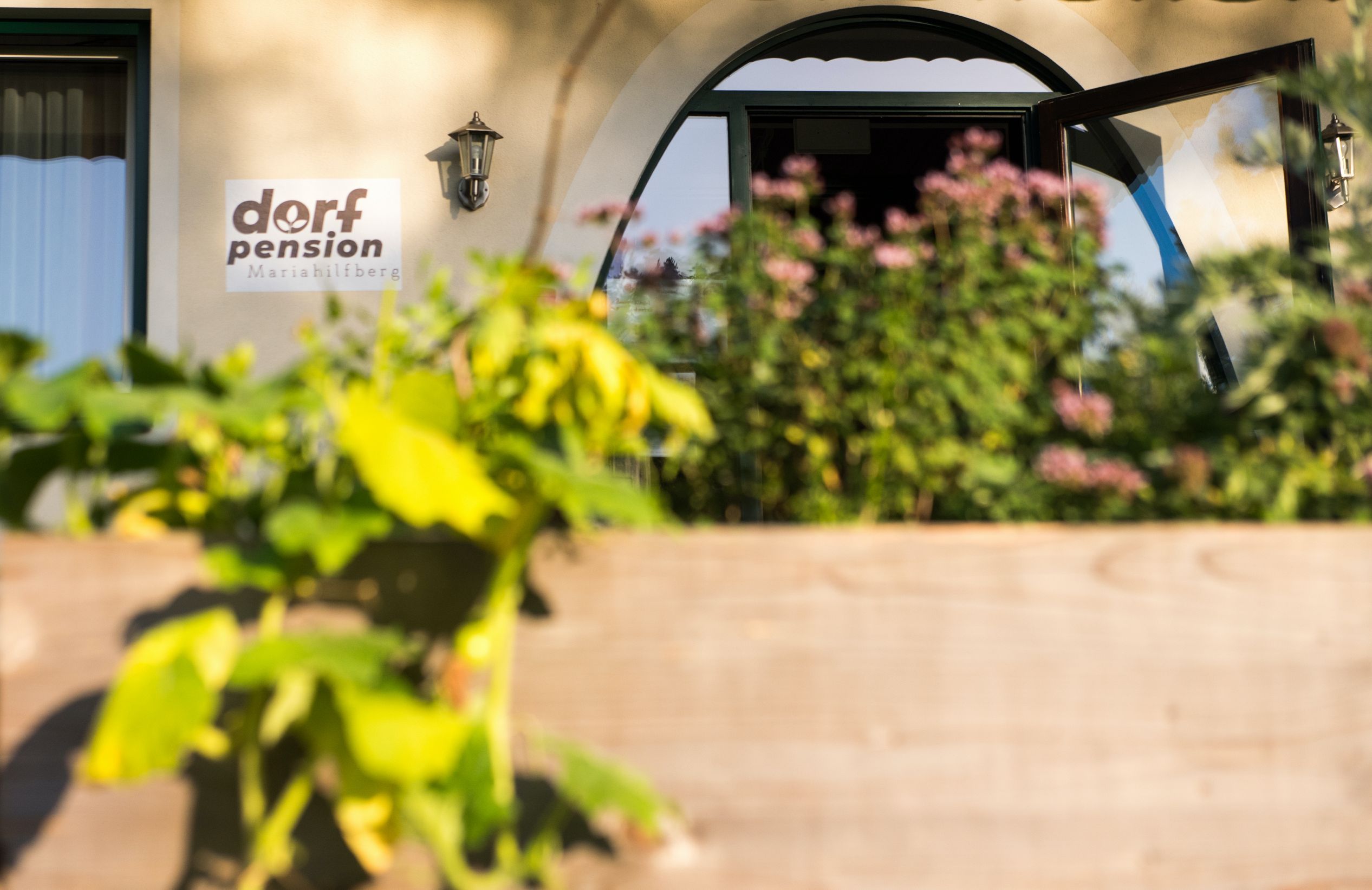 Vchod do penziónu v obci Mariahilfberg s rastlinami v popredí.