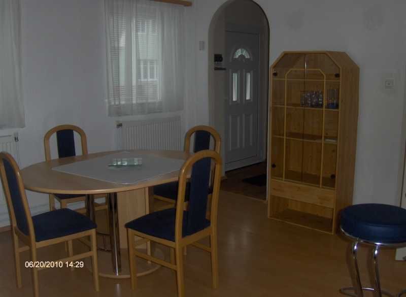 Jedálenský kút s okrúhlym stolom, štyrmi stoličkami a drevenou policou v presvetlenej miestnosti.