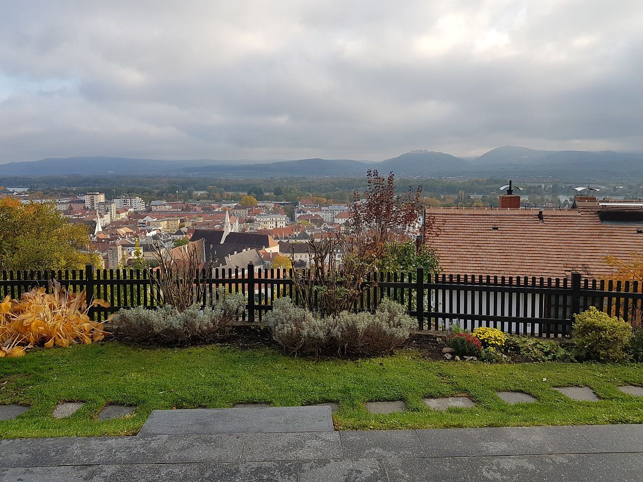 Pohľad na mesto Krems s domami, kopcami a zamračenou oblohou v pozadí.