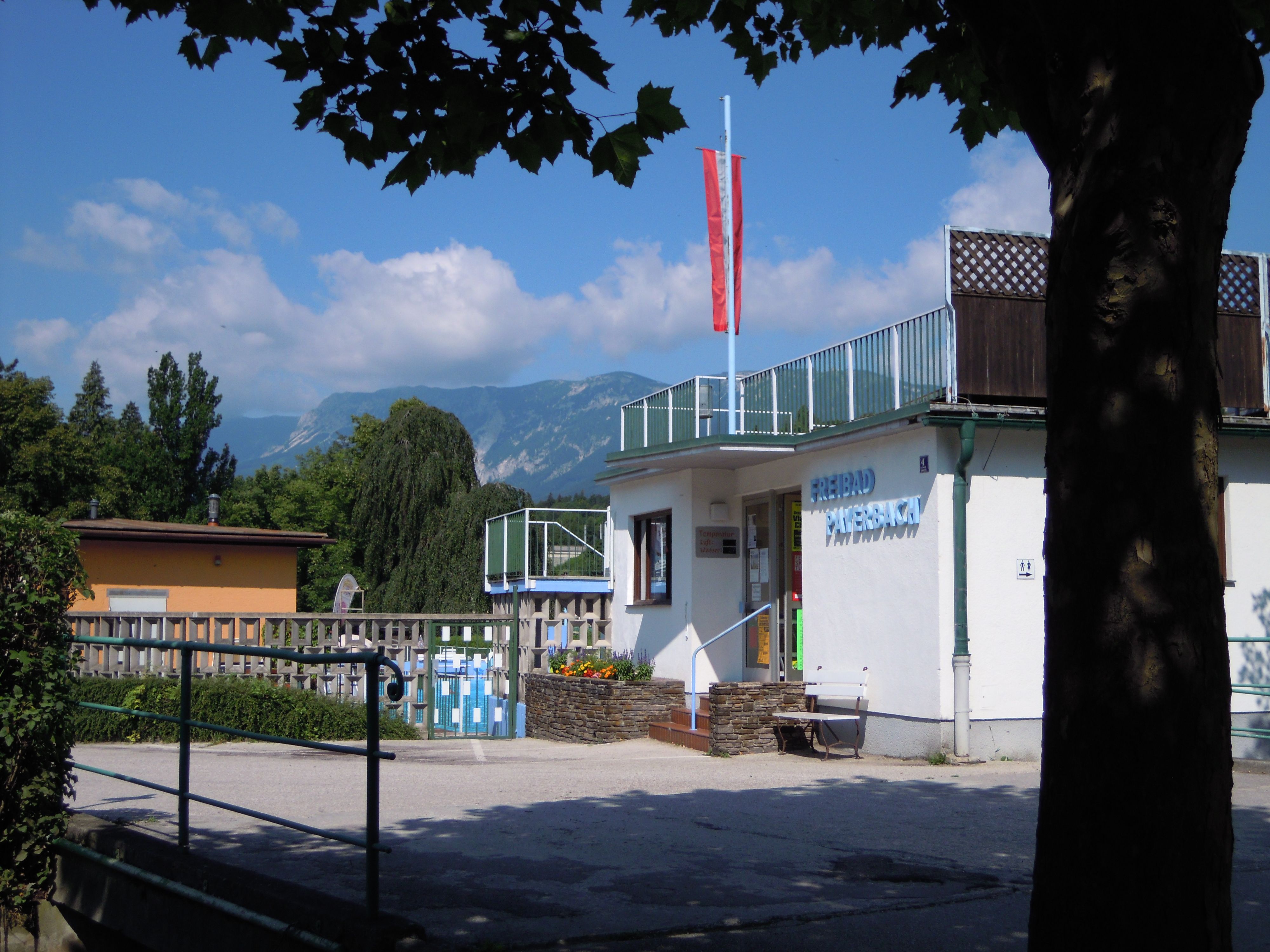 Vstup do vonkajšieho bazéna Payerbach s horskou krajinou v pozadí.