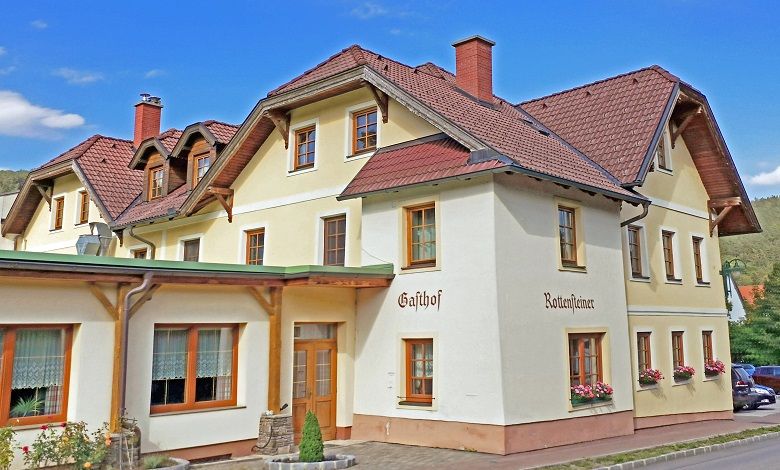 Tradičný hostinec s niekoľkými poschodiami a červenou strešnou krytinou.