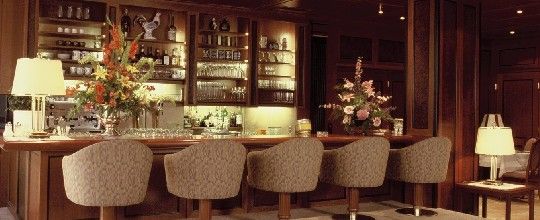 Elegantný bar s dreveným obložením, kvetinovou výzdobou a čalúnenými barovými stoličkami.