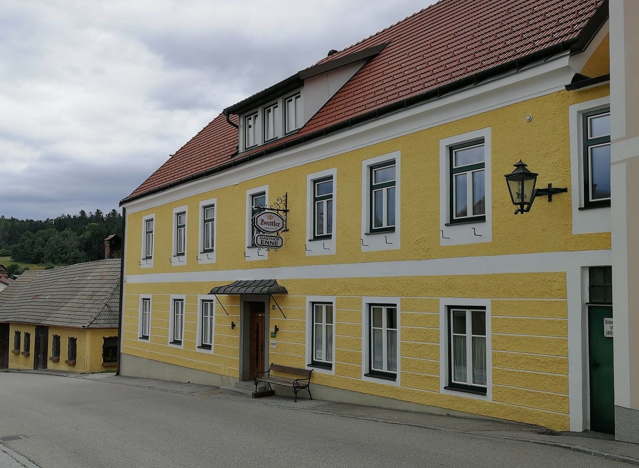 Žltá budova s nápisom "Gasthof Enne" a nápisom piva Zwettler.