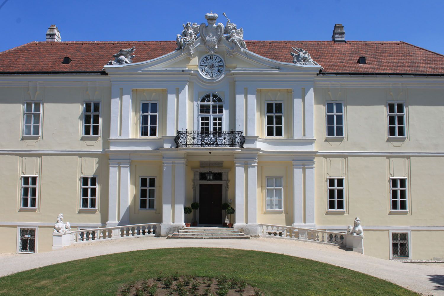 Pohľad na Lichtenštajnský hrad s hodinami a sochami na streche.