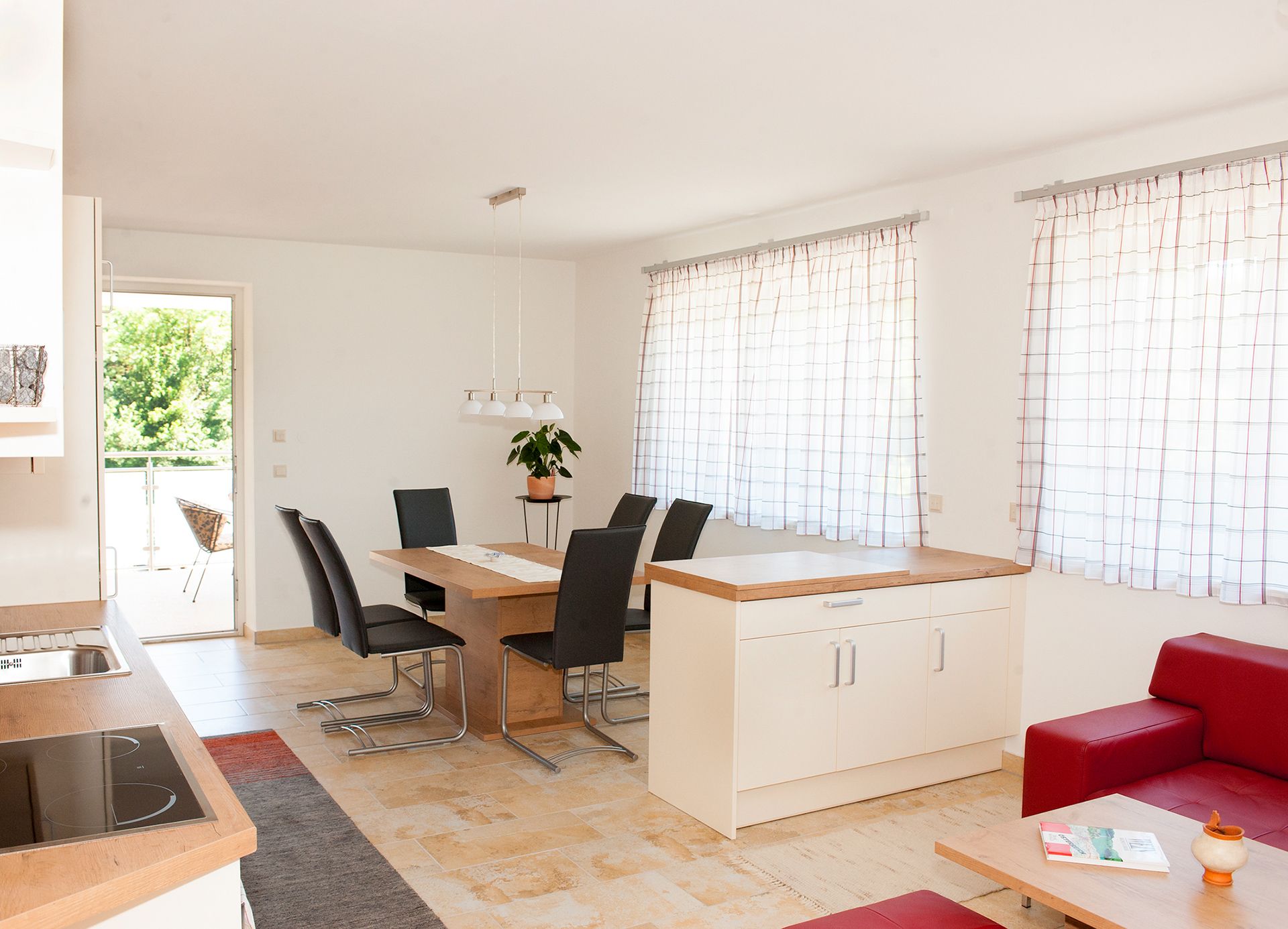 Moderná jedáleň s dreveným stolom, čiernymi stoličkami a veľkými oknami so závesmi.