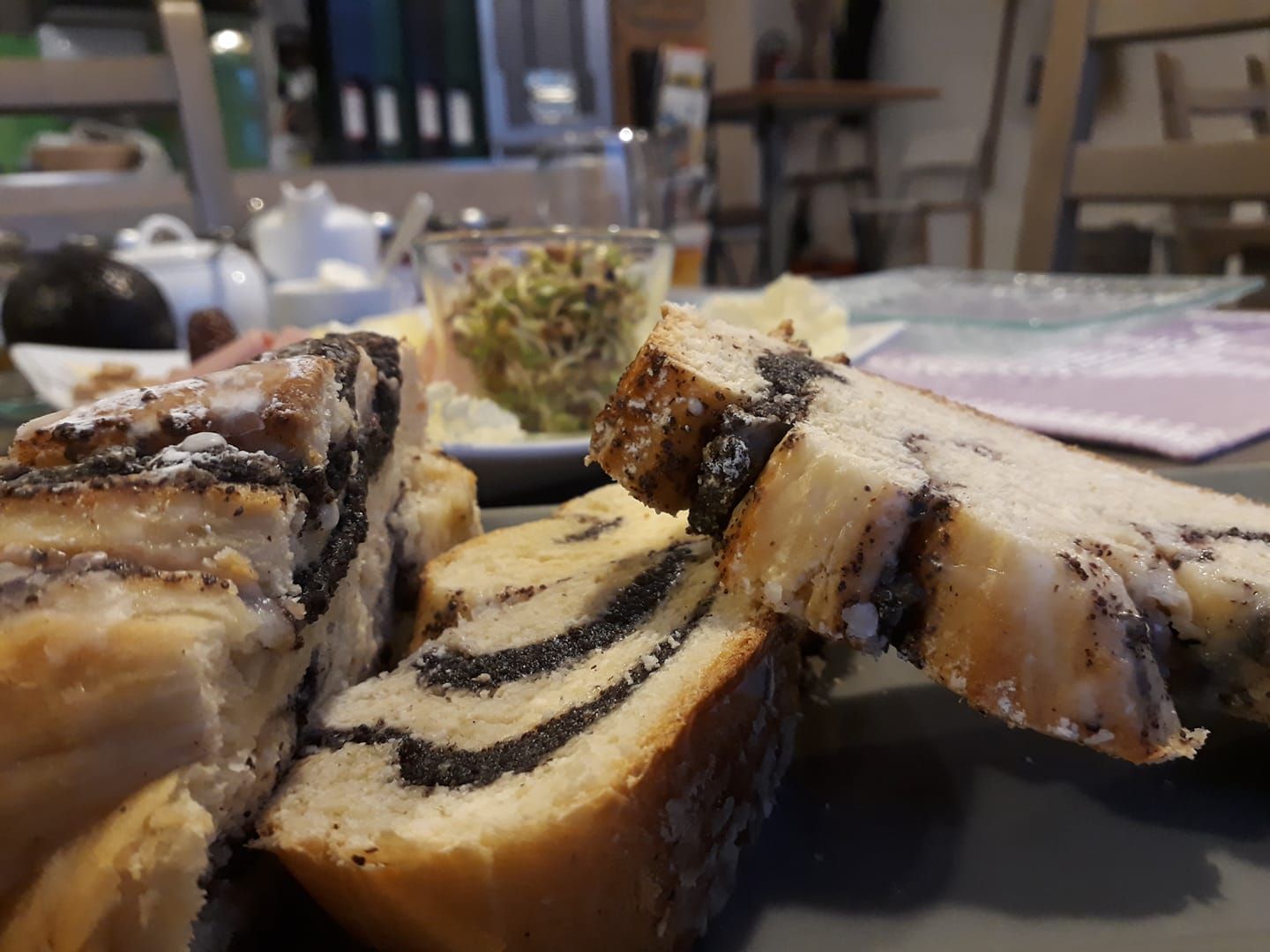 Detailný záber na makový koláč na raňajkovom stole s rozmazaným pozadím.