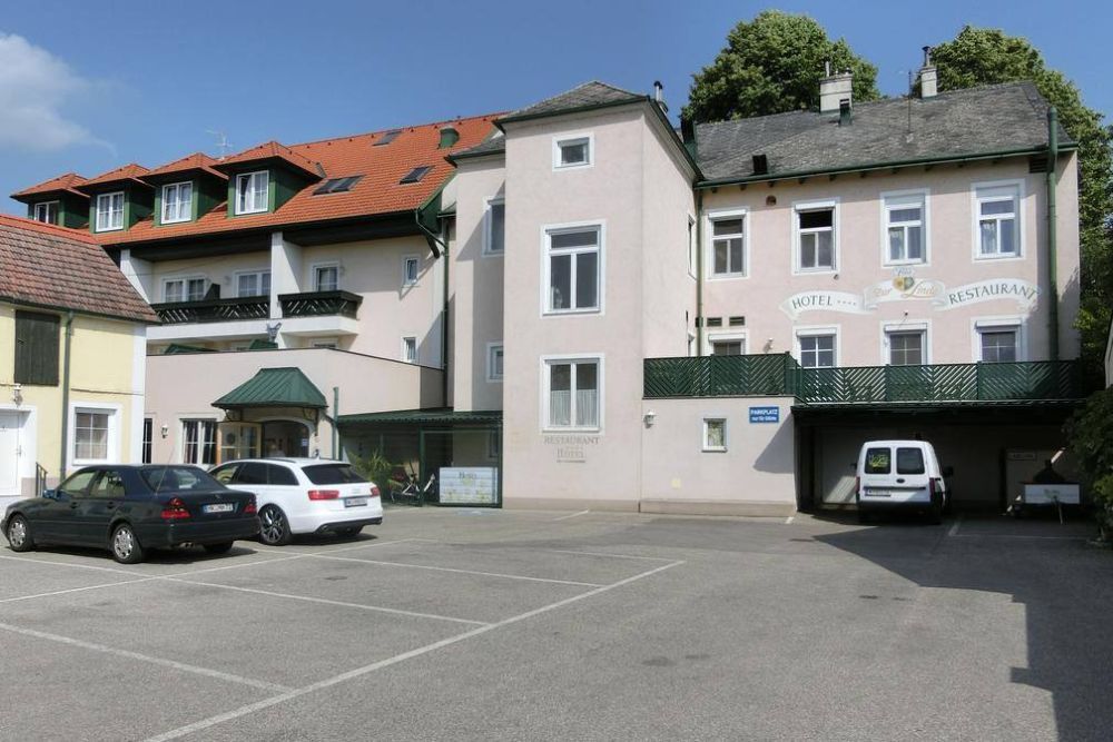Exteriérový pohľad na hotel s parkoviskom a autami.