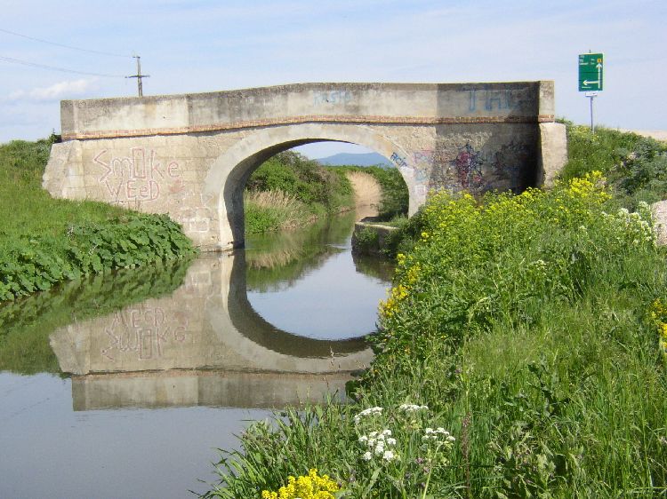Most cez kanál Wiener Neustadt v Eggendorfe s grafitmi a odrazom vo vode.