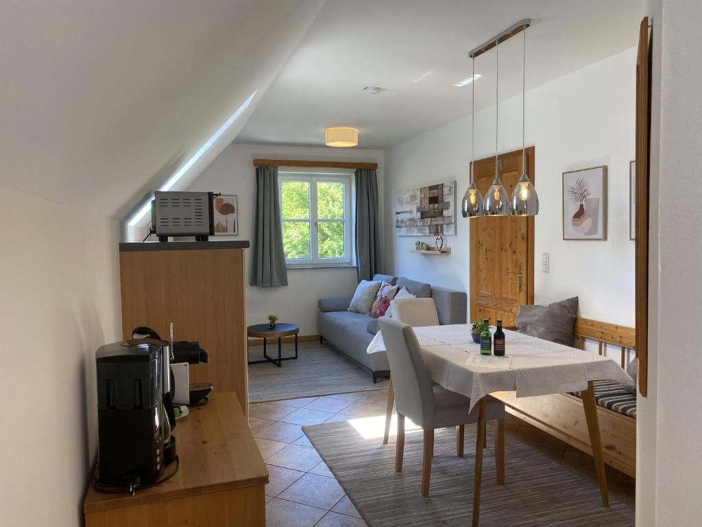 Útulná obývacia izba s jedálenským stolom, pohovkou a kuchynským kútom v štýle vidieckeho domu.