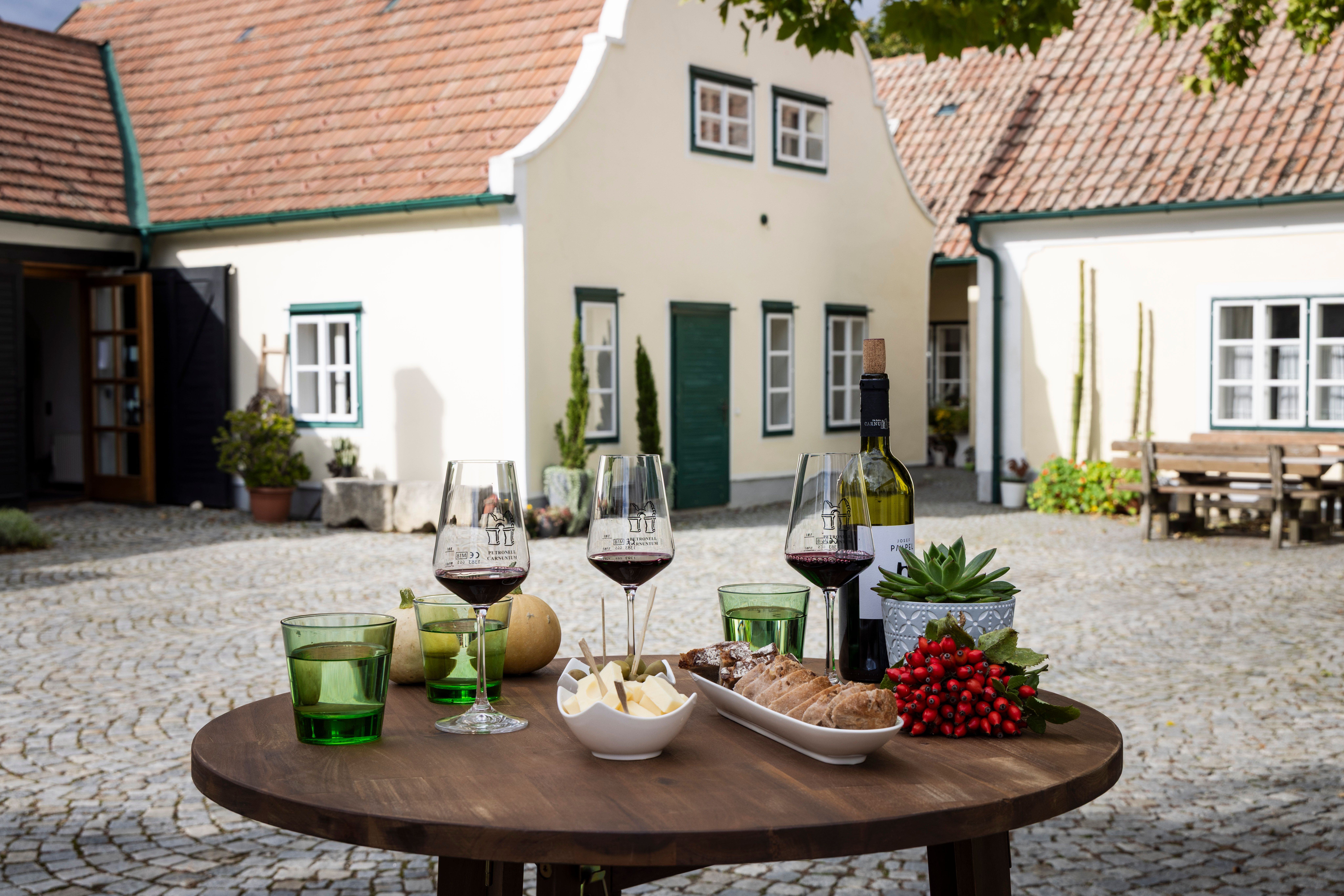 Stôl s pohármi na víno, syrom a chlebom vo vinárni na nádvorí